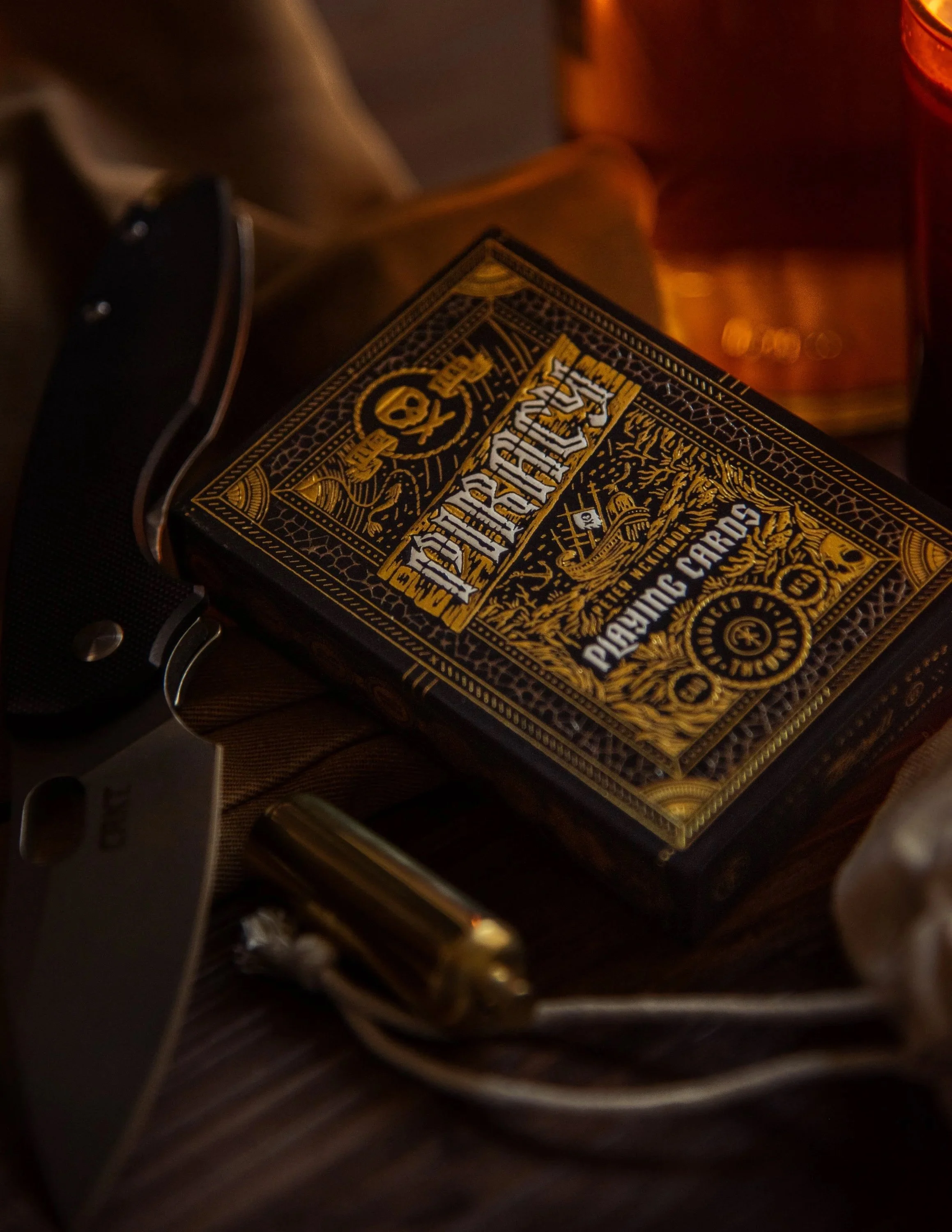 Ornate playing card box with knife and brass accents in warm firelight moody product photography