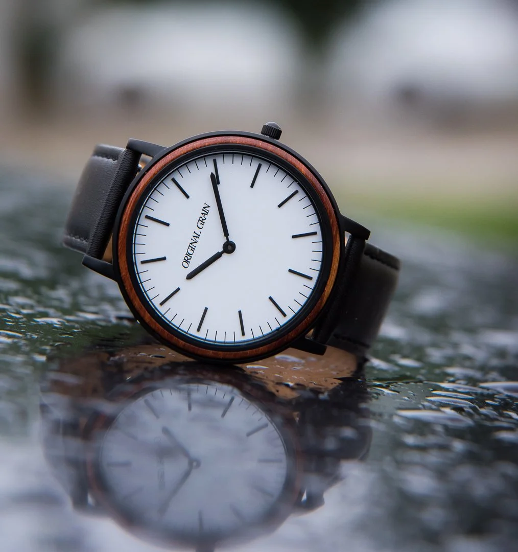 Original Grain wood watch reflecting in rain puddle on wet stone surface outdoor product photography Utah
