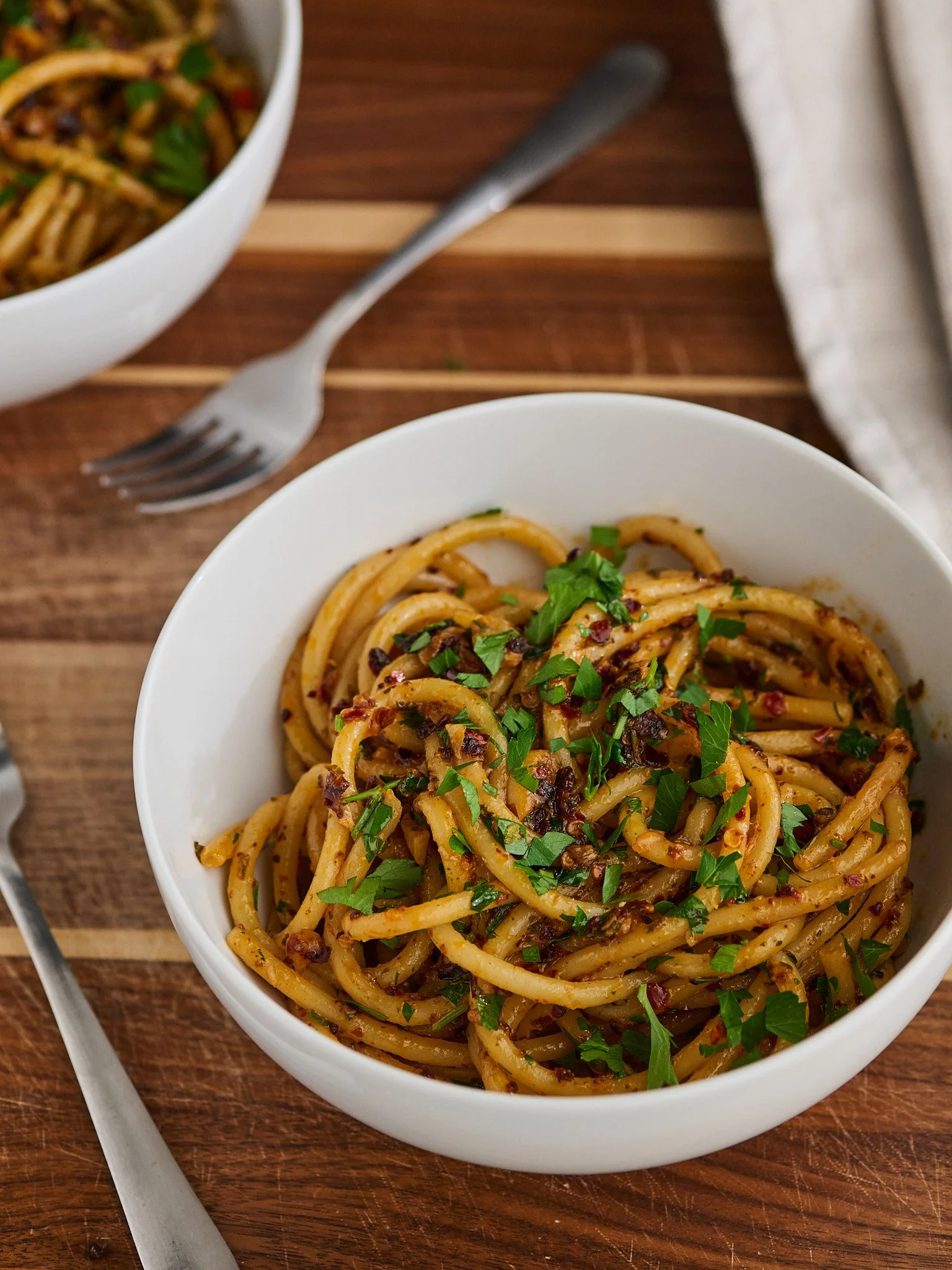 Spaghetti with herbs and chili flakes in white bowl on wooden surface food photography Salt Lake City
