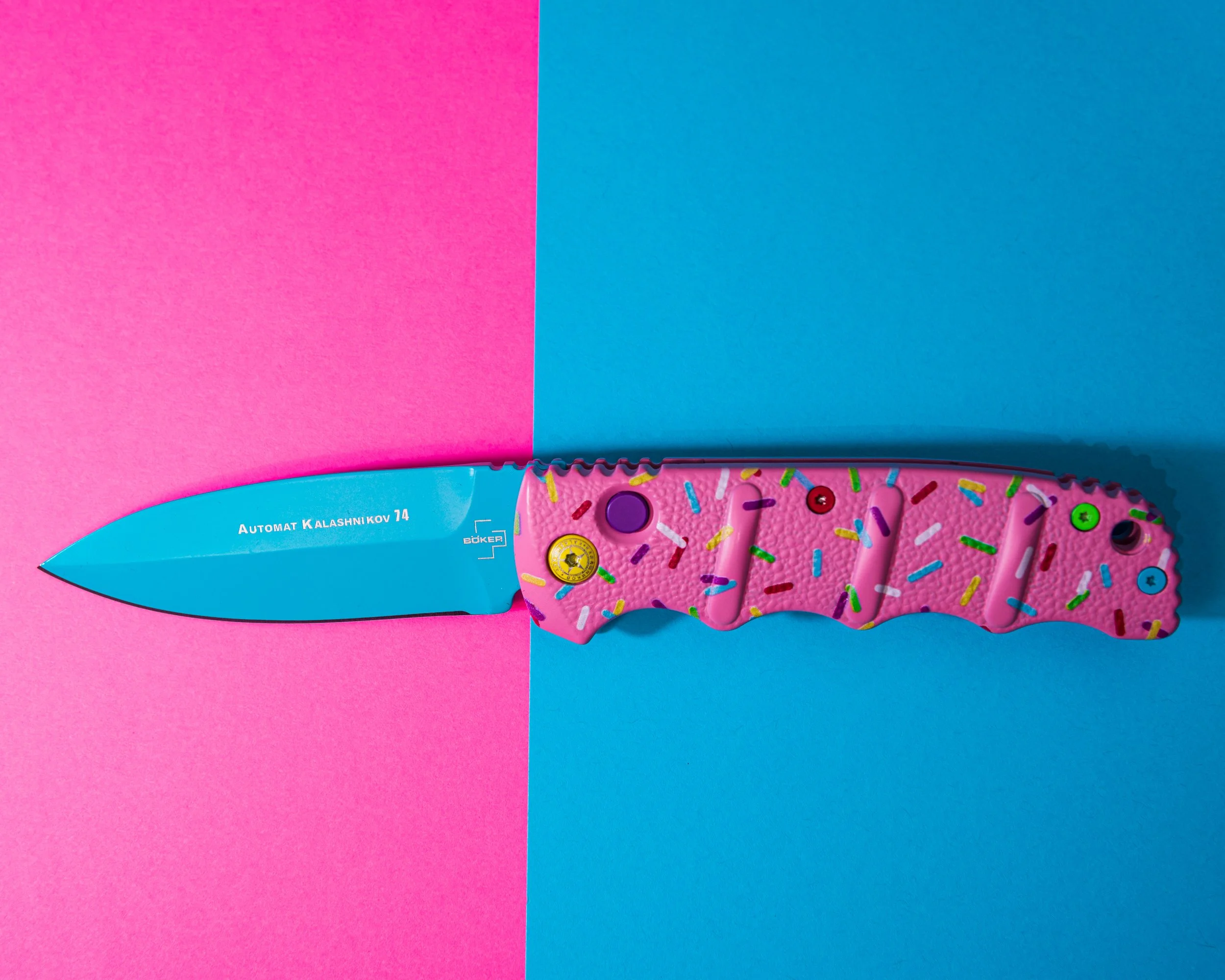 Pink sprinkle handled Boker folding knife on split pink and blue background creative product photography