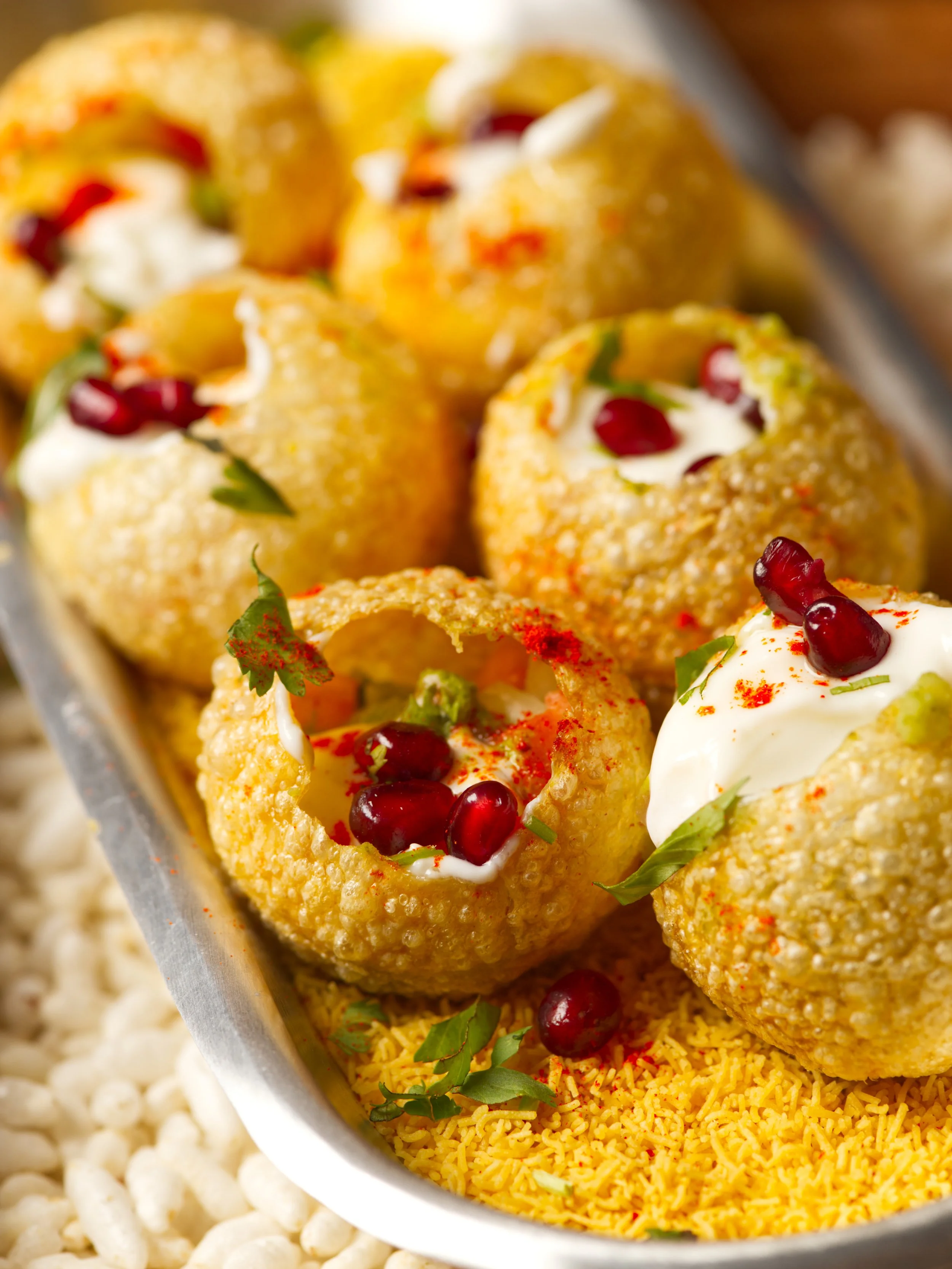 Indian street food pani puri with pomegranate seeds yogurt and spices in silver tray food photography Salt Lake City