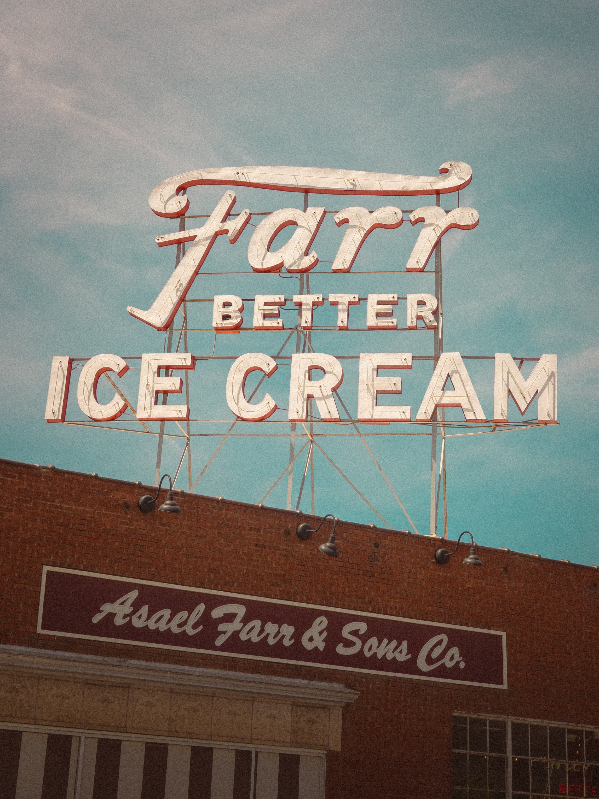 The vintage neon sign for Farr Better Ice Cream rises above a brick storefront in Ogden, Utah, its white and red lettering catching a moody blue sky. The Asael Farr & Sons Co. marquee anchors the facade below.