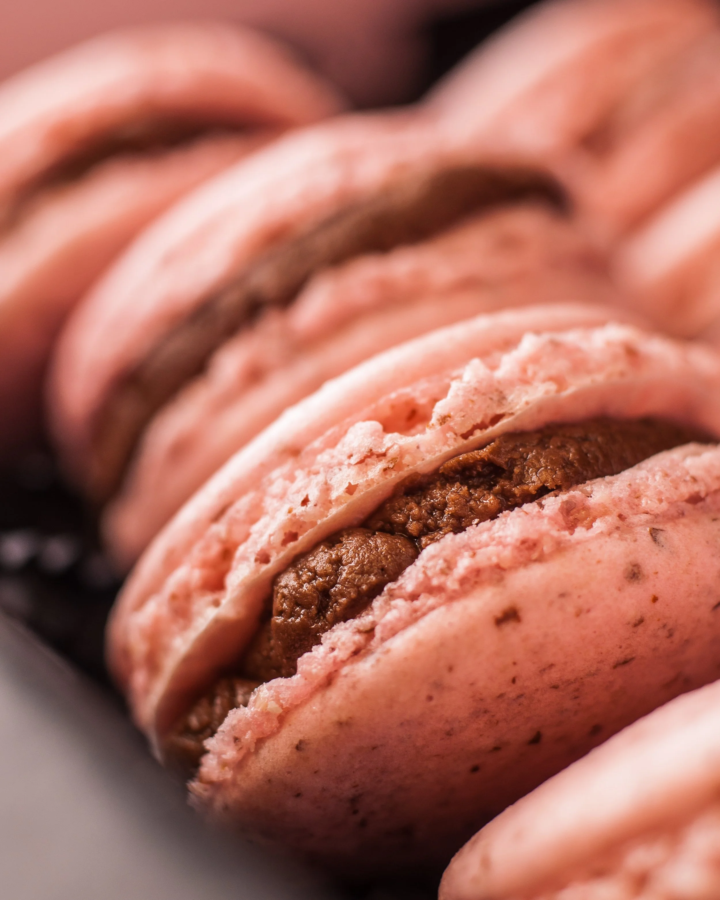 Pink strawberry macarons close up showing texture and chocolate filling detail food photography