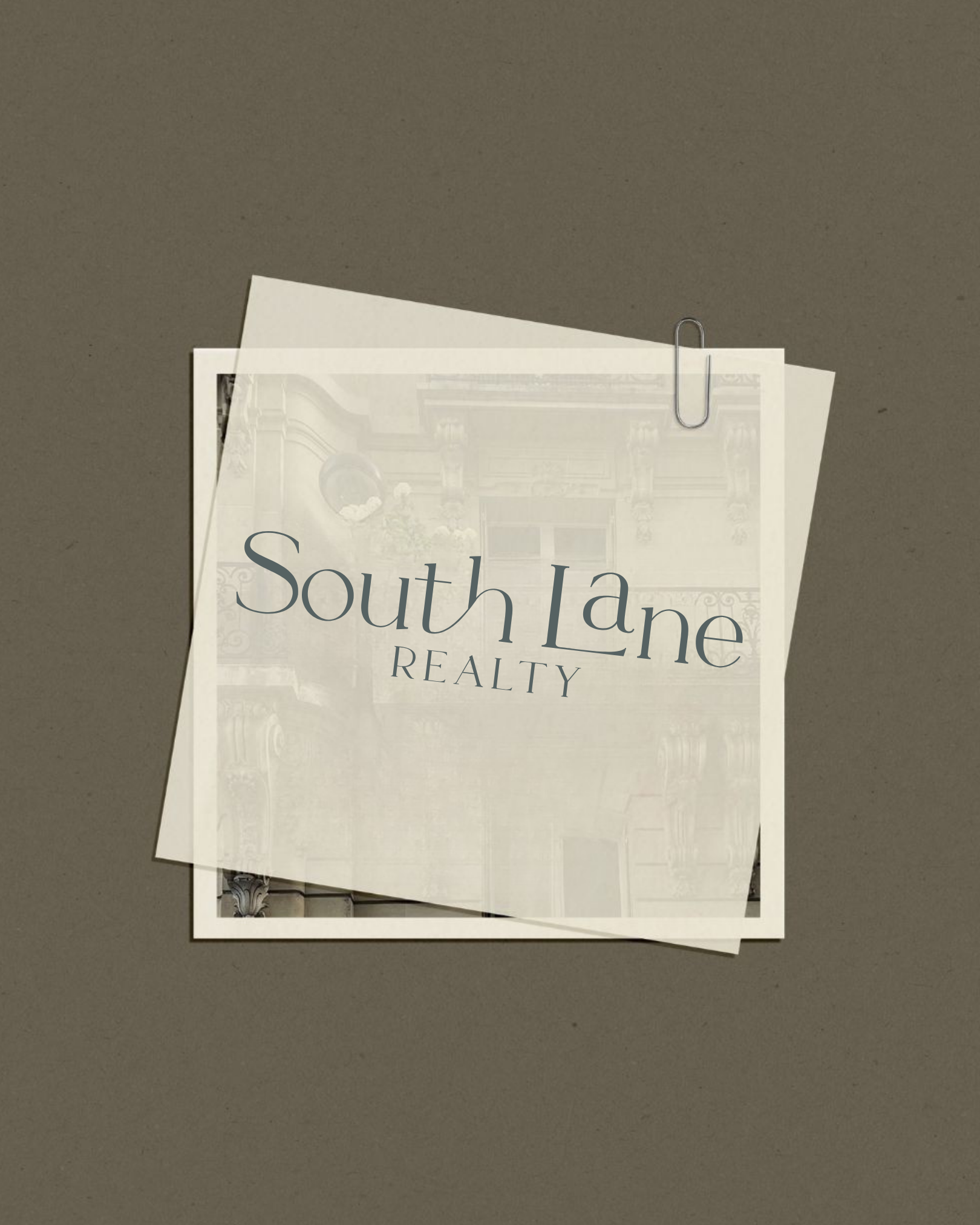 A paper with the text "South Lane Realty" on it, held by a paperclip, set against a dark gray background.