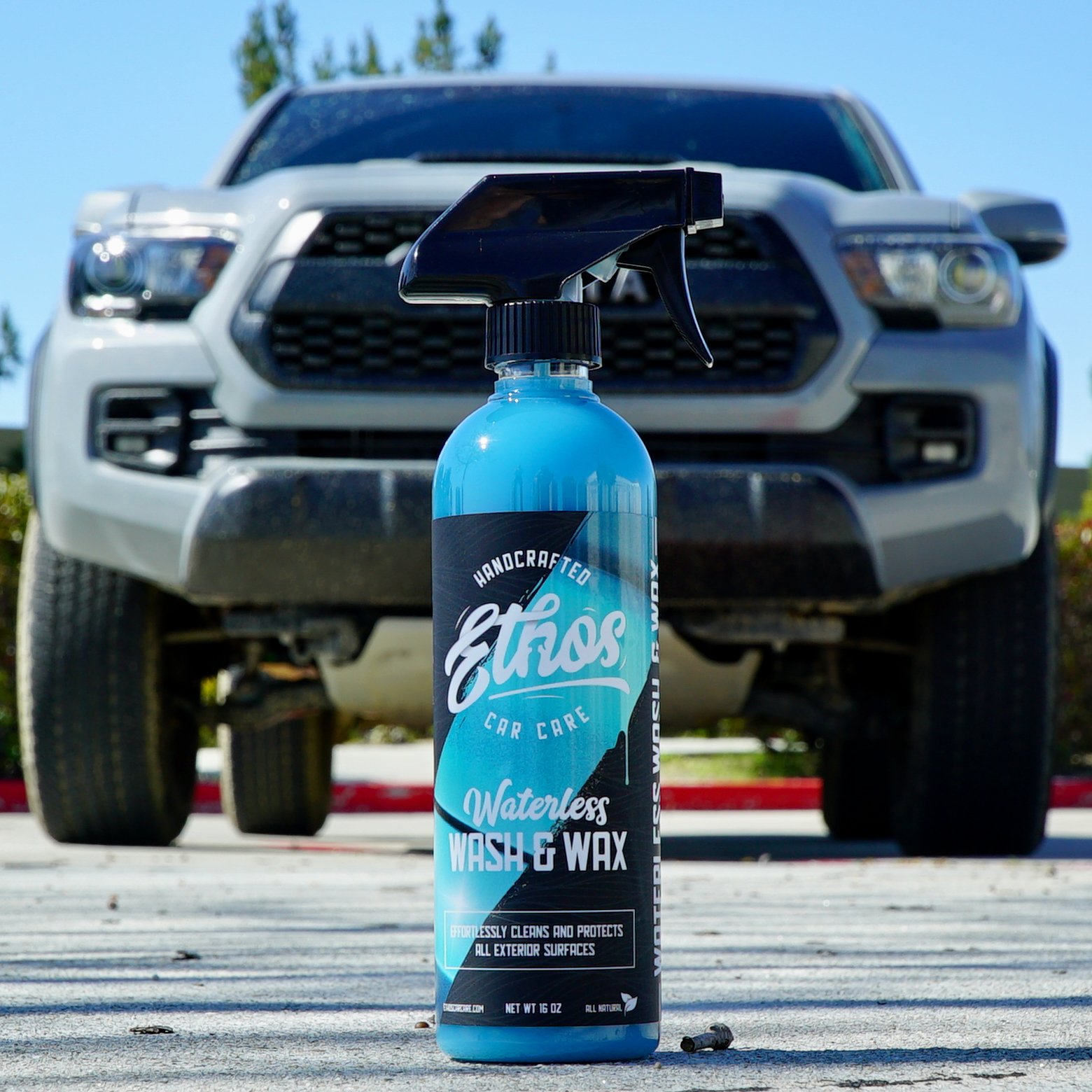 A bottle of Ethos Waterless Wash & Wax car cleaning spray in front of a white truck.