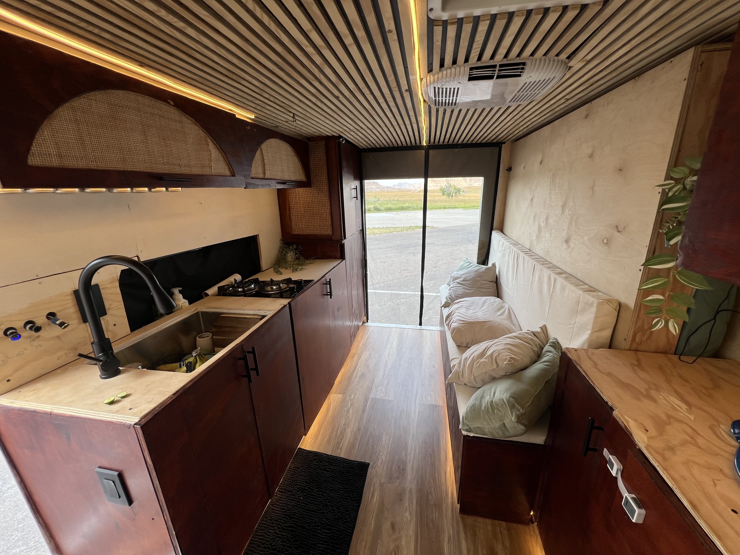 Interior of a small, cozy living space with a kitchen area and a sofa, featuring wooden accents and a large window showing an outdoor landscape.  Elopement photo / pictures/ pic