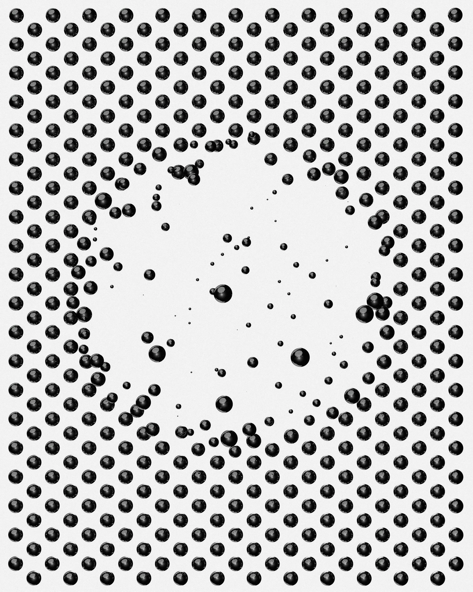 A pattern of black spheres on a white background, with some smaller spheres scattered around.