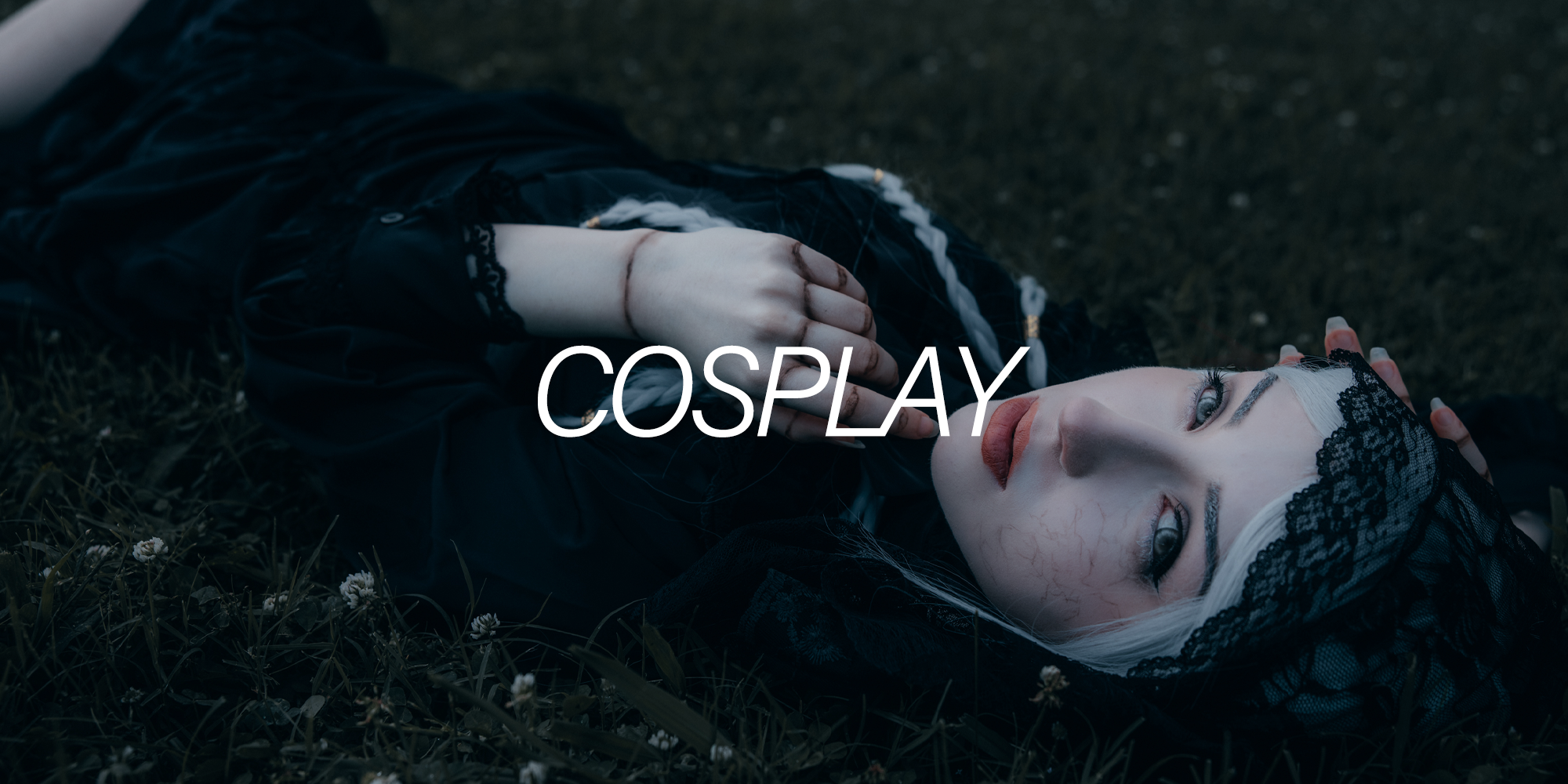 Person lying on grass in cosplay costume with a black lace headpiece, white hair, and makeup, with the word 'COSPLAY' overlaid.