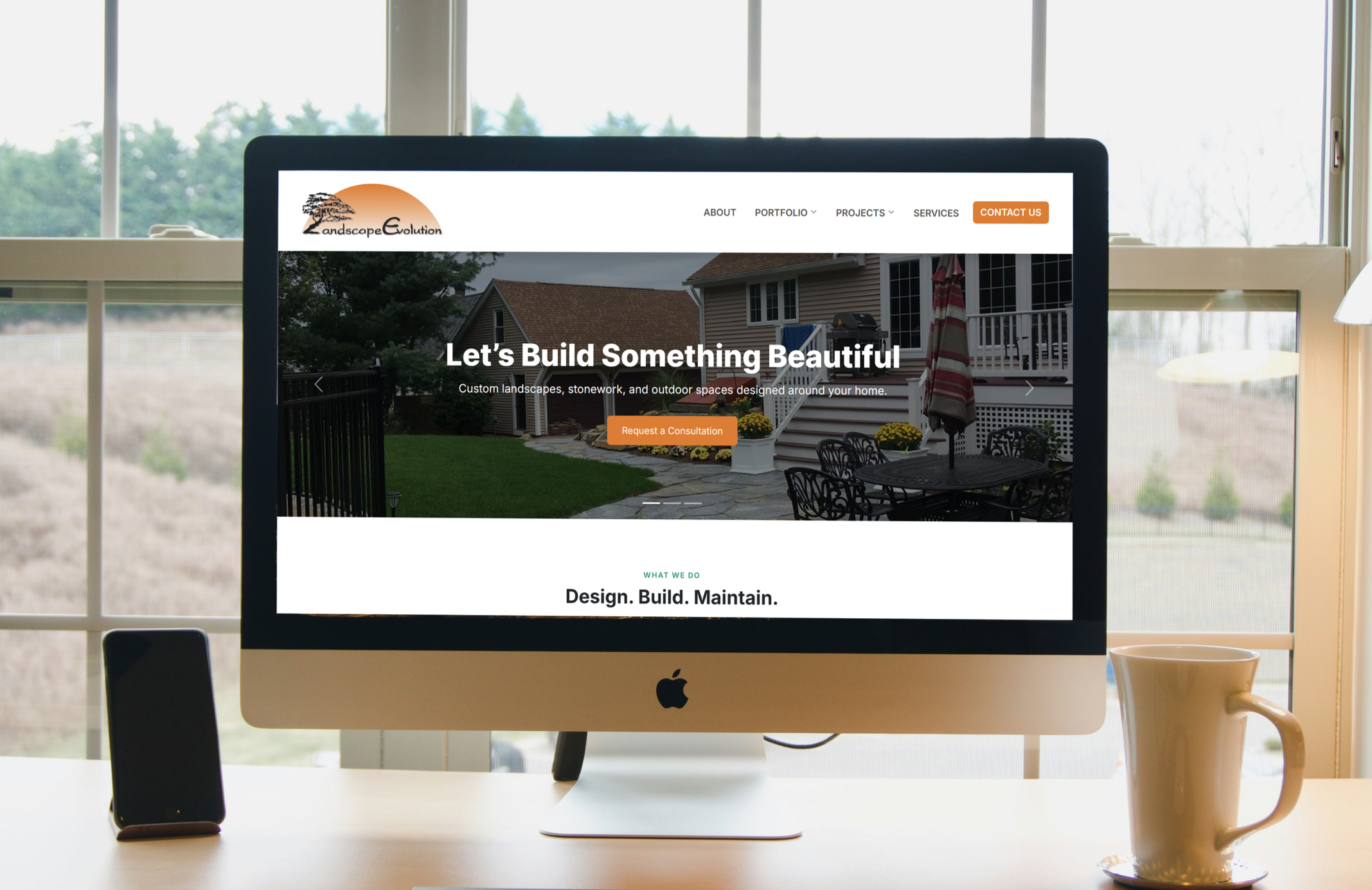 Computer screen displaying a landscaping company's website with an outdoor backyard showing a patio, house, and garden.