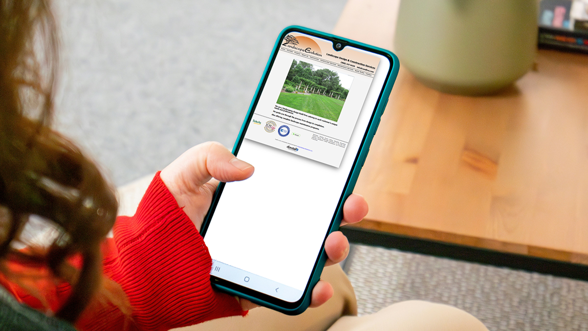 Person holding a smartphone displaying a website with a picture of a grassy field and trees.