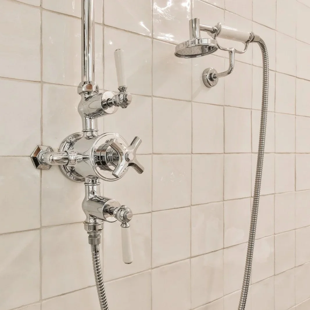 Chrome thermostatic shower valve with handheld showerhead installed on tiled bathroom wall during Maine shower plumbing upgrade project.