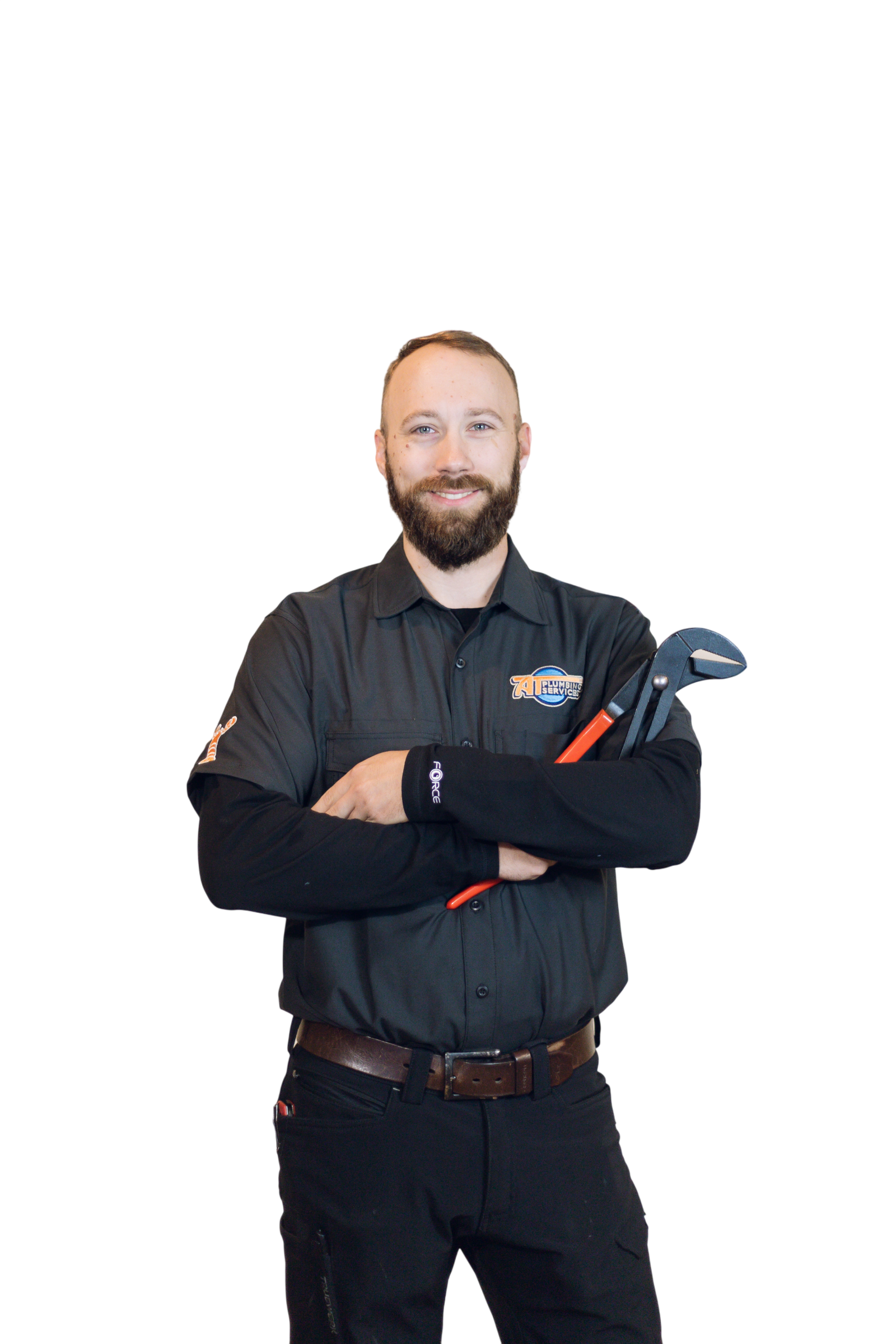 A smiling man with a beard and short hair, wearing a black uniform with a logo on the chest, holding a pipe wrench with his arms crossed.