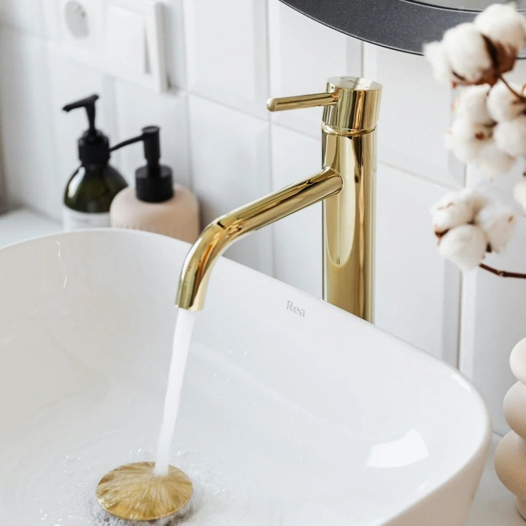 Modern gold bathroom faucet installed on white sink during residential plumbing fixture replacement and bathroom upgrade project in older home.