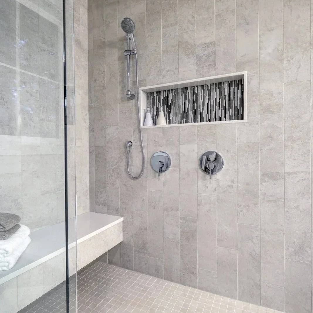 Modern walk-in shower with tiled walls, glass enclosure, and plumbing fixtures installed during residential bathroom renovation project in Maine.