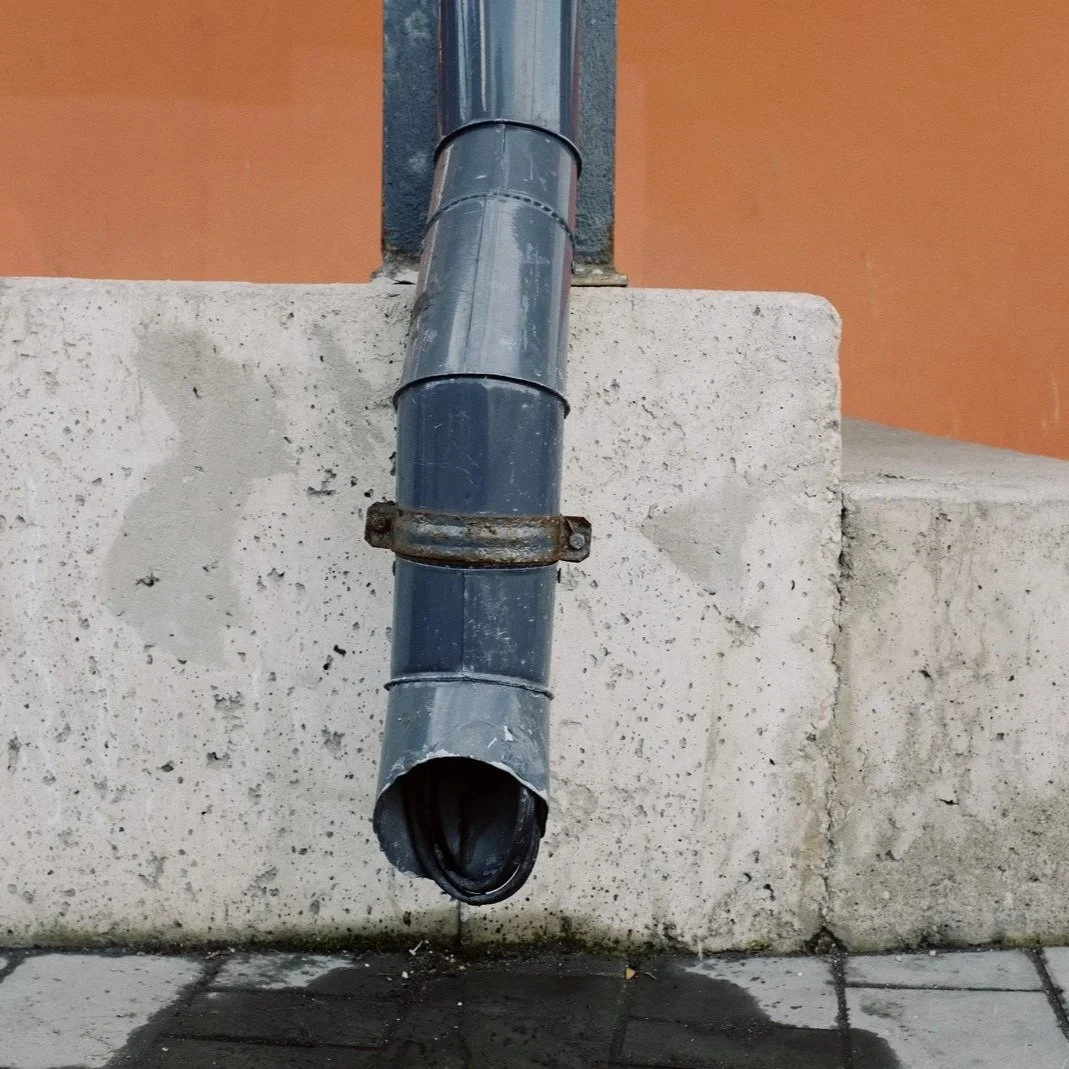 Exposed exterior drain pipe on older building highlighting plumbing drainage infrastructure often evaluated during residential bathroom remodel projects.