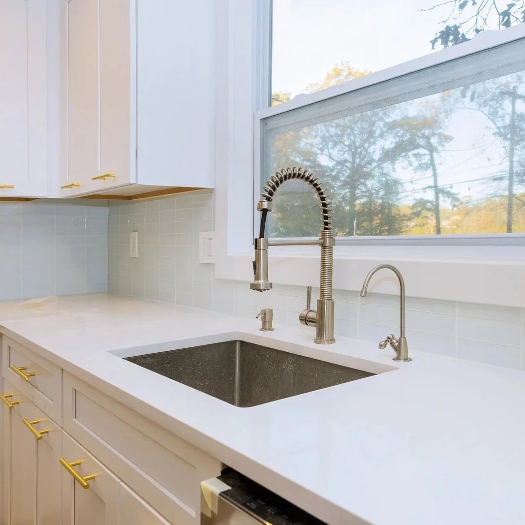 Modern kitchen sink with pull-down faucet and white countertops during Maine kitchen plumbing relocation and renovation installation project.