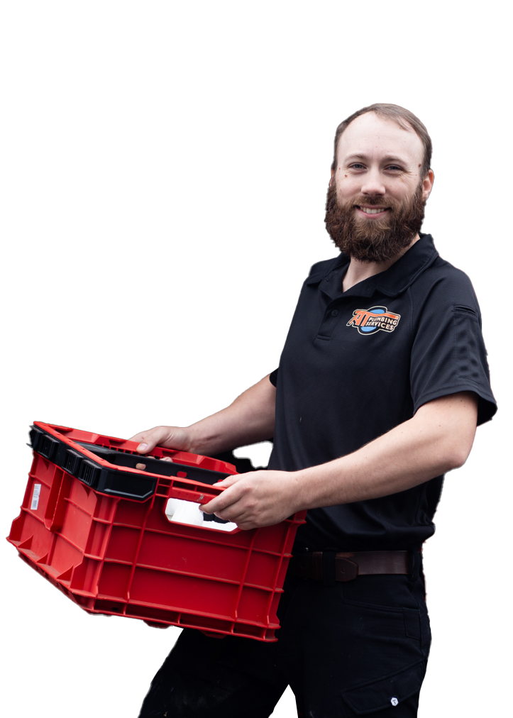 A man with a beard smiling while holding a red plastic storage crate, wearing a black polo shirt with a company logo.