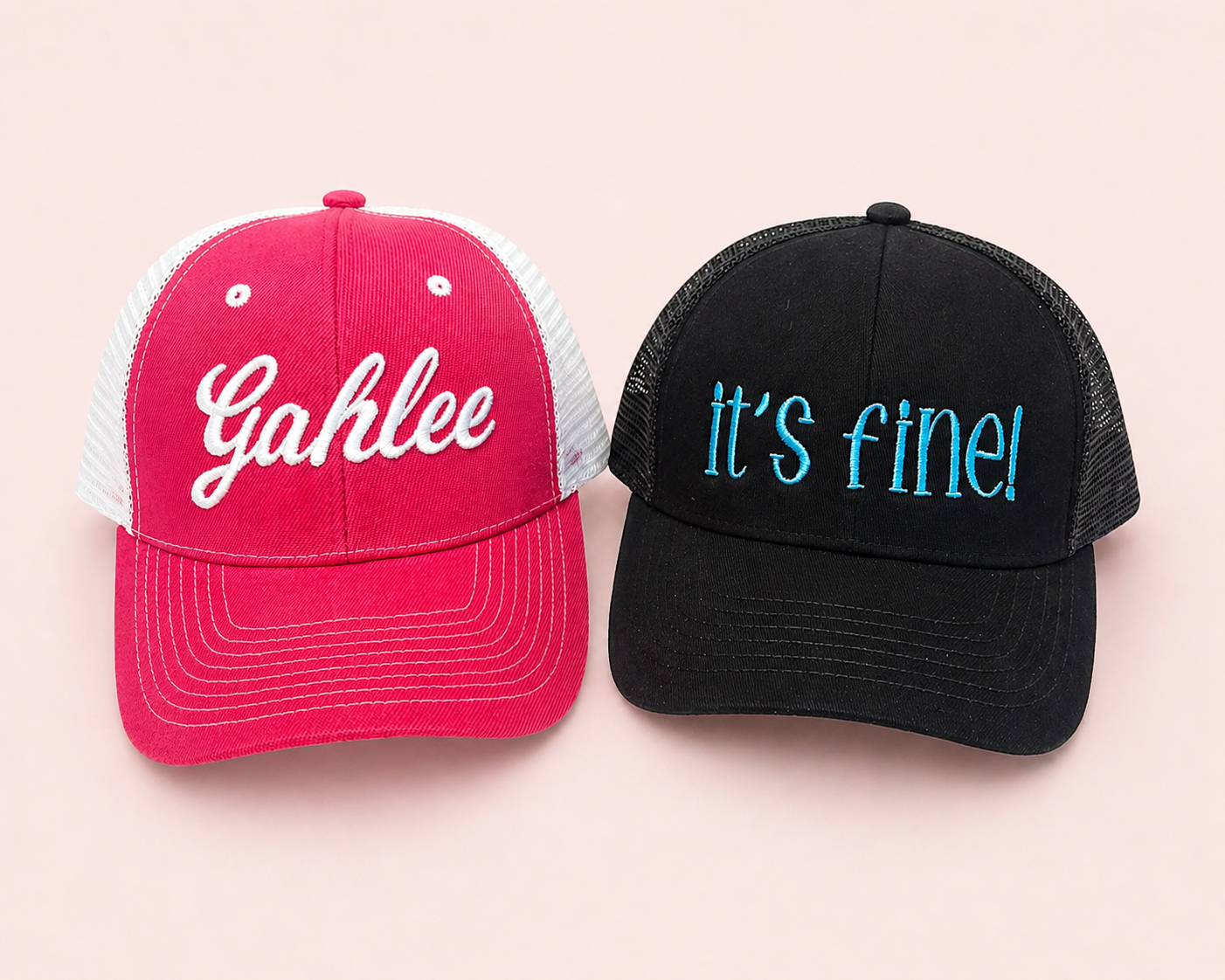 Custom embroidered trucker hats in pink and black with stitched lettering designs
