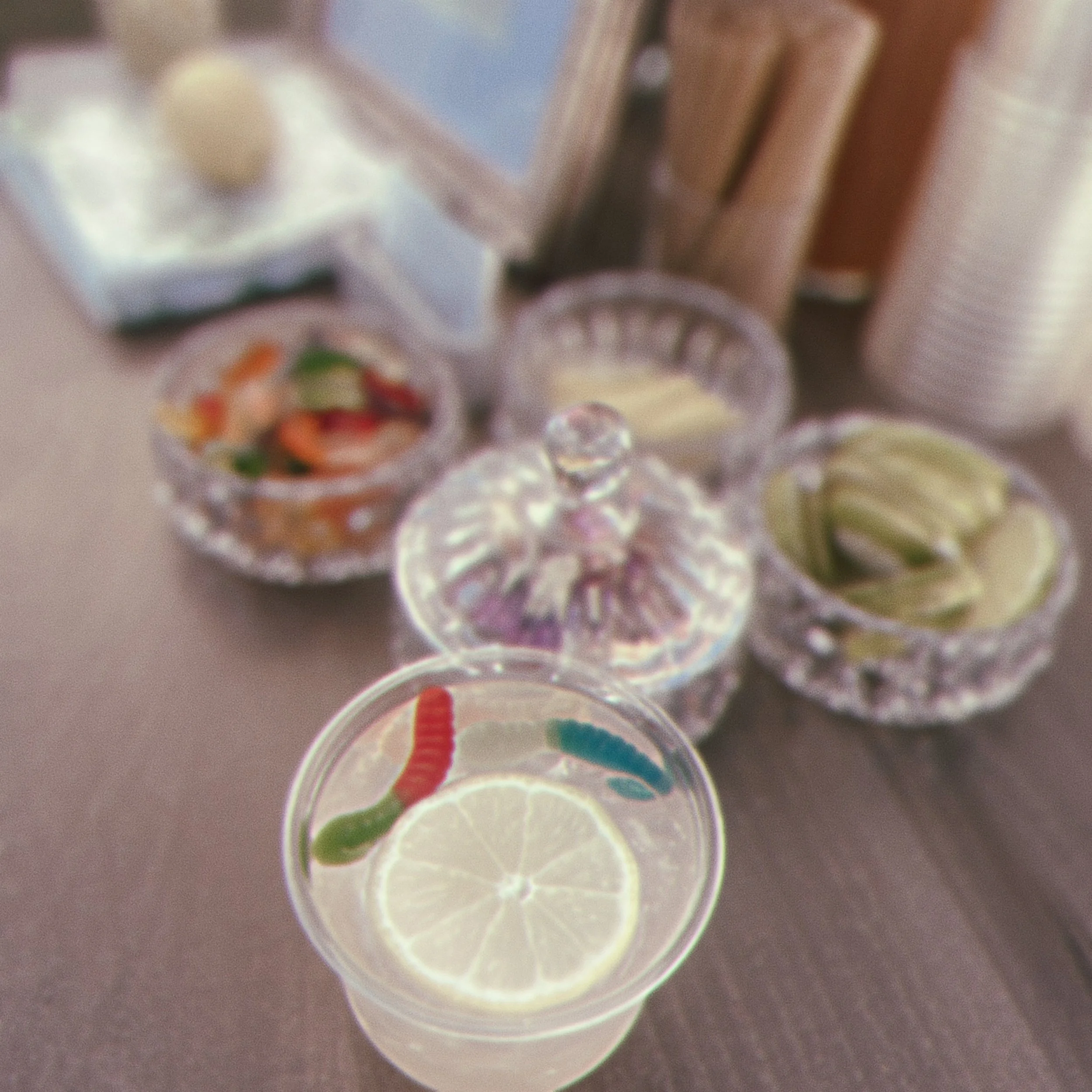 Colorful candies in small transparent cups arranged on a surface, with lemon slices placed nearby.