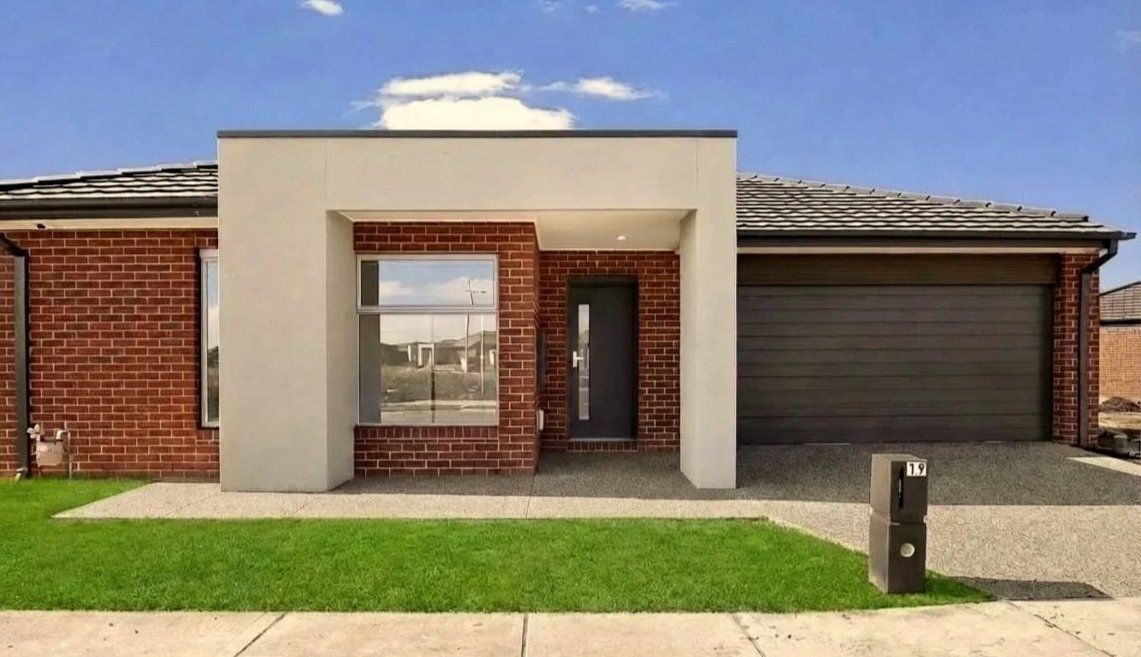 Modern single-story house with red brick exterior, a large front window, a dark front door, and a two-car garage, with a small front lawn and a driveway.
