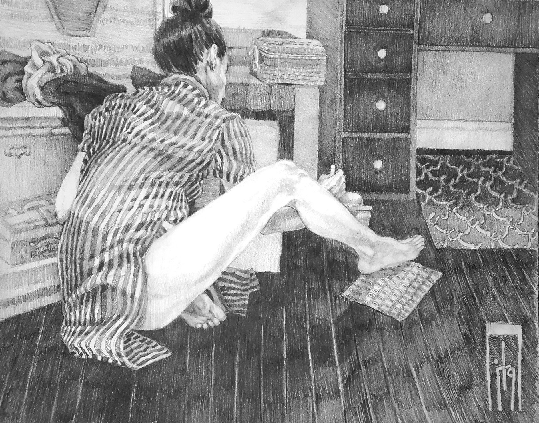 A person with dark hair tied in a bun, wearing a striped shirt, is kneeling on floor. The room contains furniture such as a dresser with drawers, a woven basket, and various objects like a stack of books or magazines and a patterned rug.