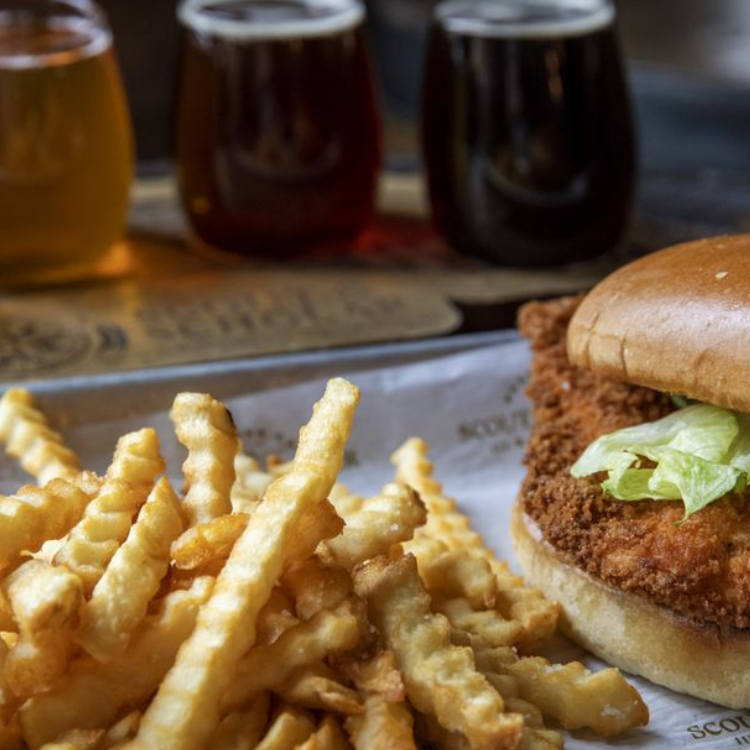 Fried chicken sandwich with crinkle‑cut fries and a flight of beers at Scout & Scholar Brewing Company in Bardstown, Kentucky.