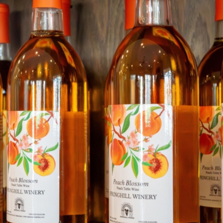 Peach Blossom wine bottles displayed as part of the Springhill tasting experience with bright peach‑themed labels.