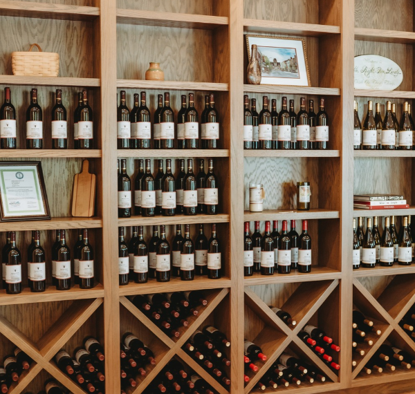 Wooden wine racks filled with bottles of wine, some standing upright on shelves and others lying horizontally in cubbies.