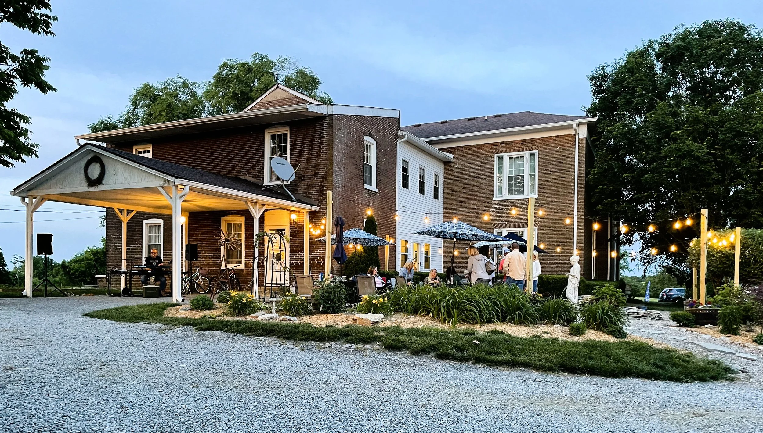 Guests enjoying an early‑evening gathering with live music, string lights, and outdoor seating as part of the Springhill hospitality experience.