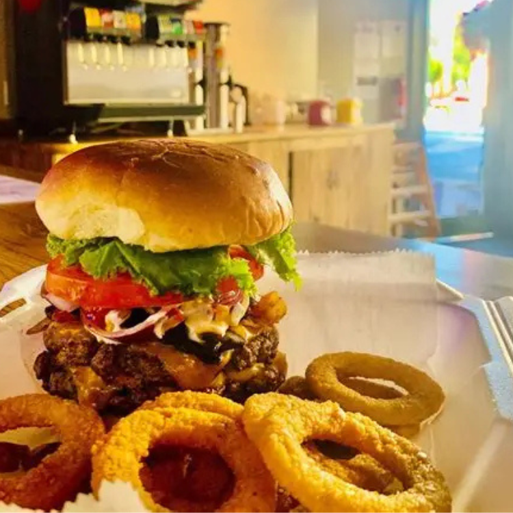 Cheeseburger with onion rings served at Bardstown Burger in Bardstown, Kentucky, with drink dispensers and condiments in the background.