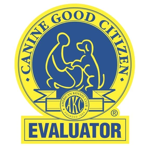 A circular logo with a yellow border and blue background. The text "Canine Good Citizen" is around the top of the circle. Inside, there is an outline of a person and a dog sitting and facing each other. Below, there is a smaller circle with the initials "AKC" for American Kennel Club and the words "Founded 1884." Beneath the main circle, a yellow rectangle with the word "Evaluator" in bold blue letters.