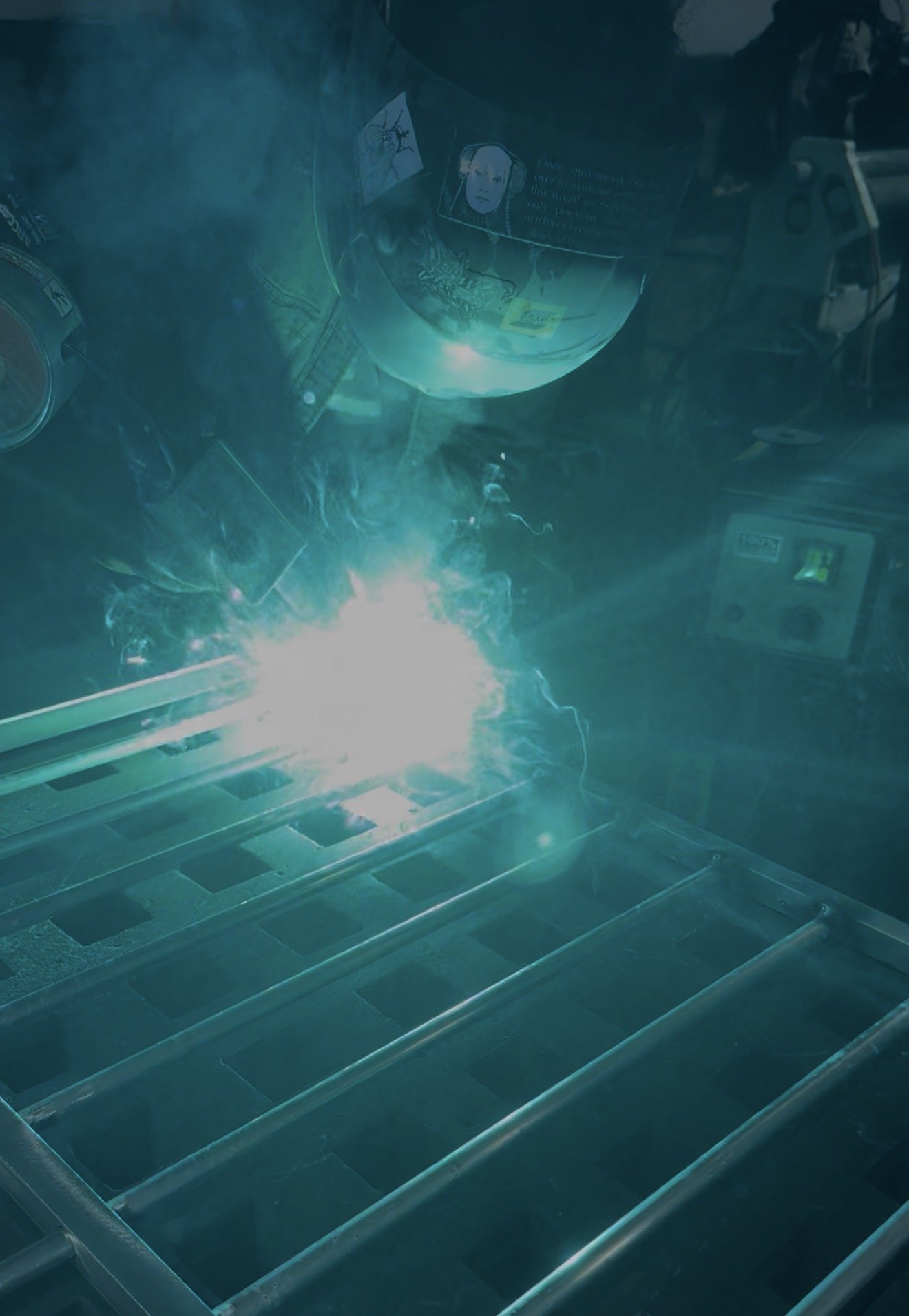 A person wearing a helmet with a reflection showing a face inside, possibly a demonstration of welding or some safety procedure, with sparks and bright light at the bottom of the image.