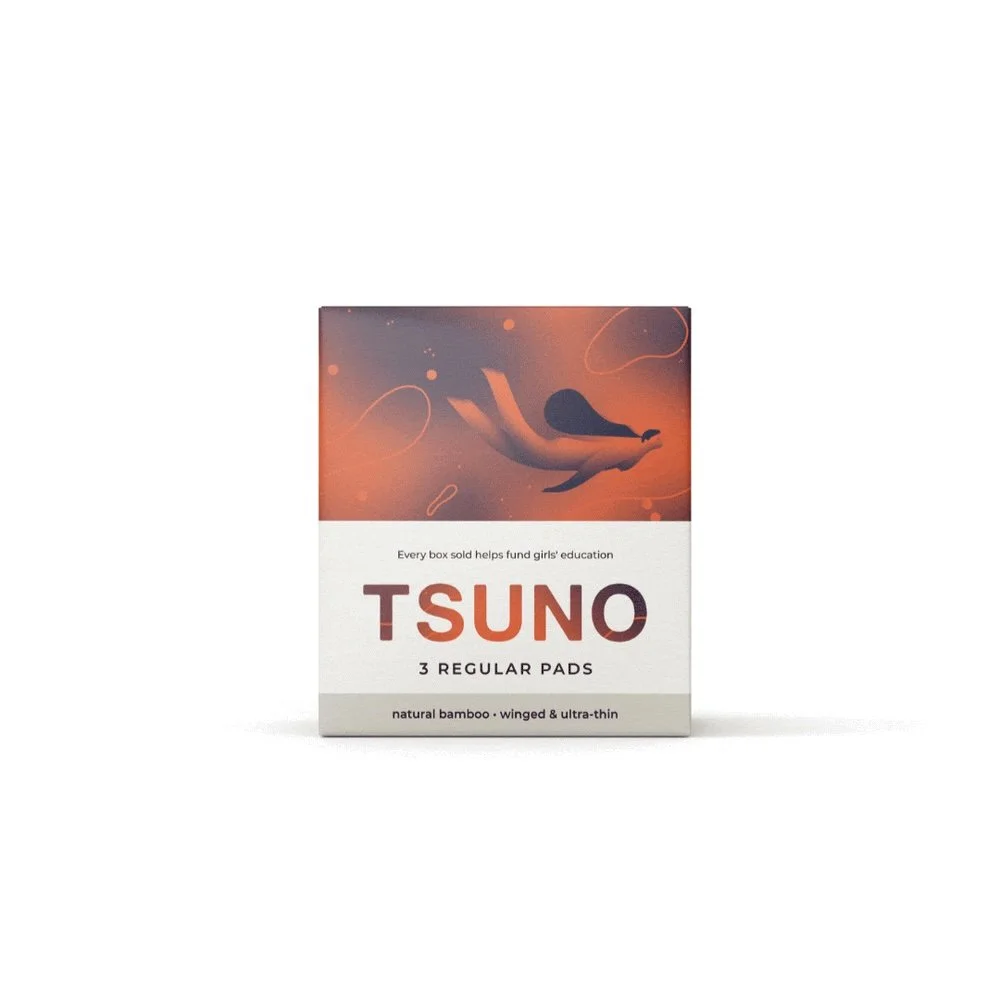 Box of Tsuno brand menstrual pads, featuring a stylized illustration of a whale swimming in an abstract, orange-toned background on the packaging.