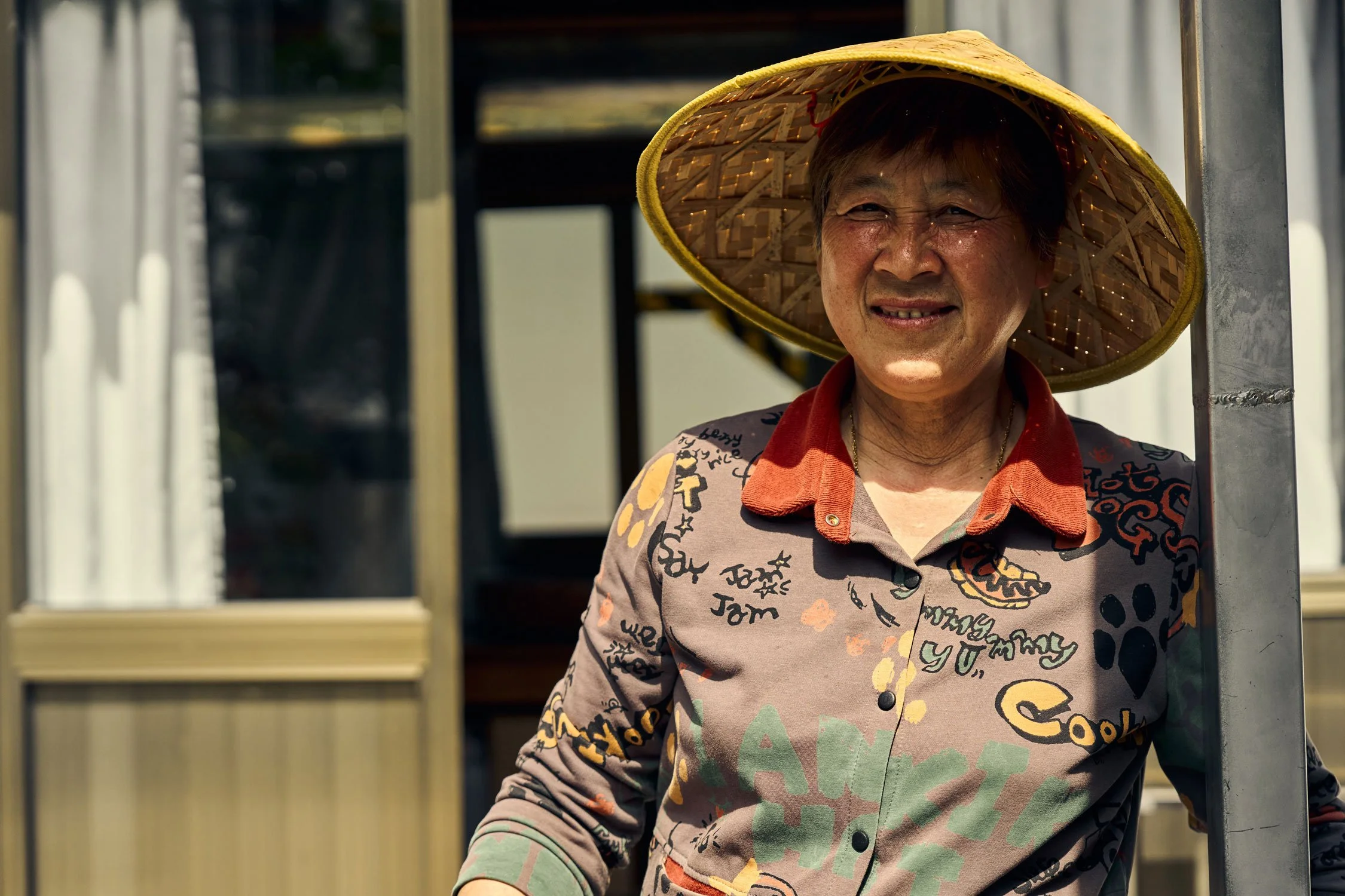  Outside her home with her bamboo hat 