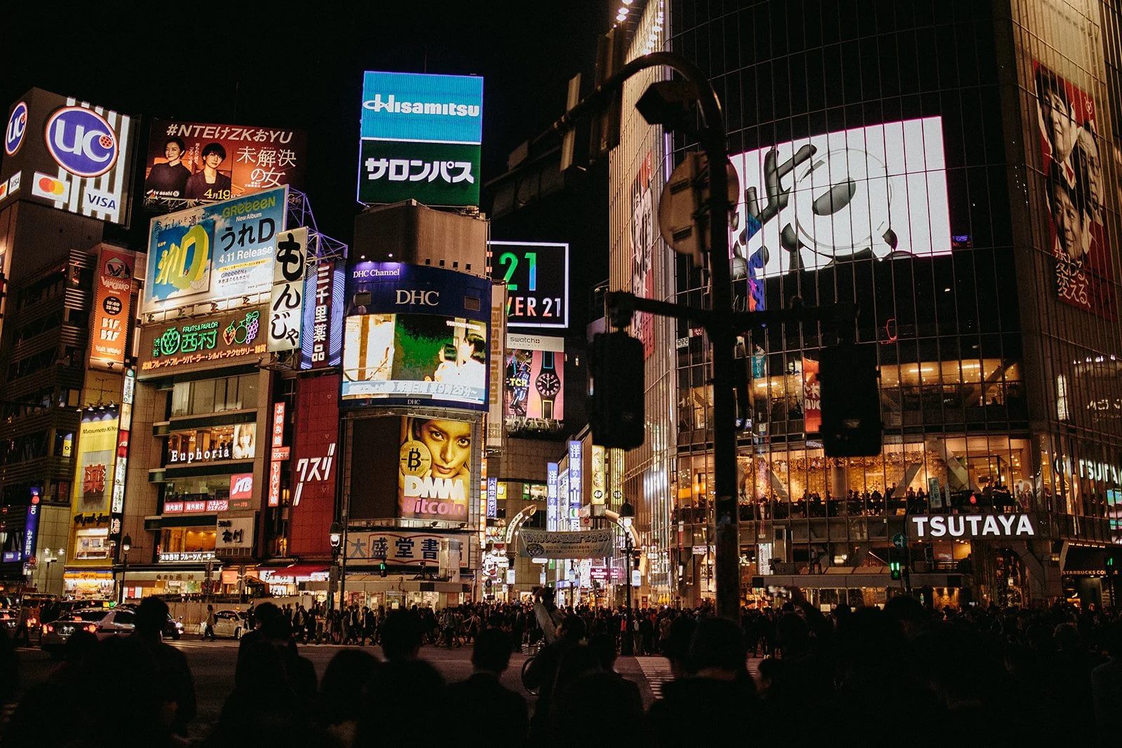 Shibuya Crossing at night in Tokyo, lit up with neon signage and crowds of pedestrians
