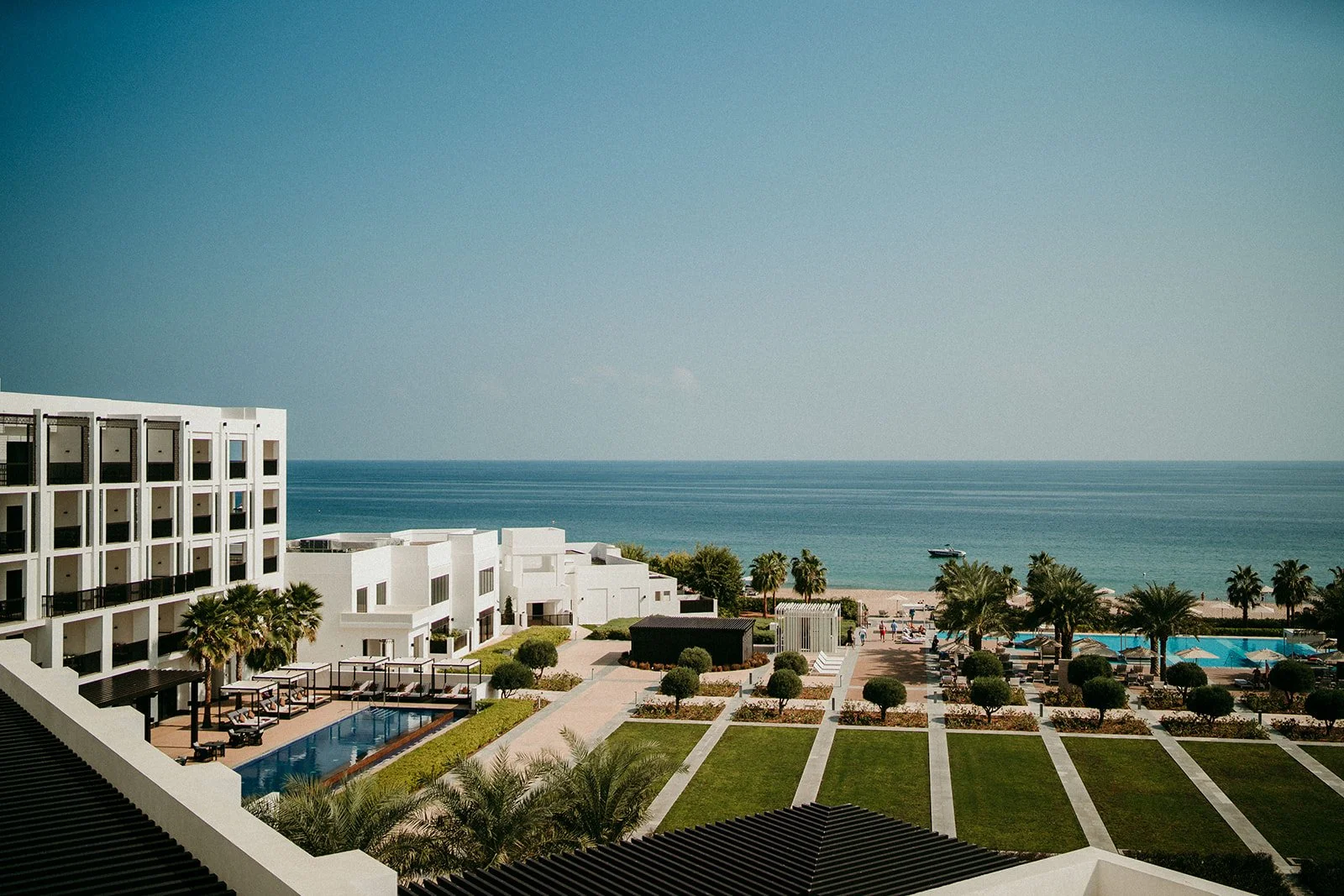 Aerial view of a beachfront resort in Dubai with manicured gardens, pool, and the Arabian Gulf coastline