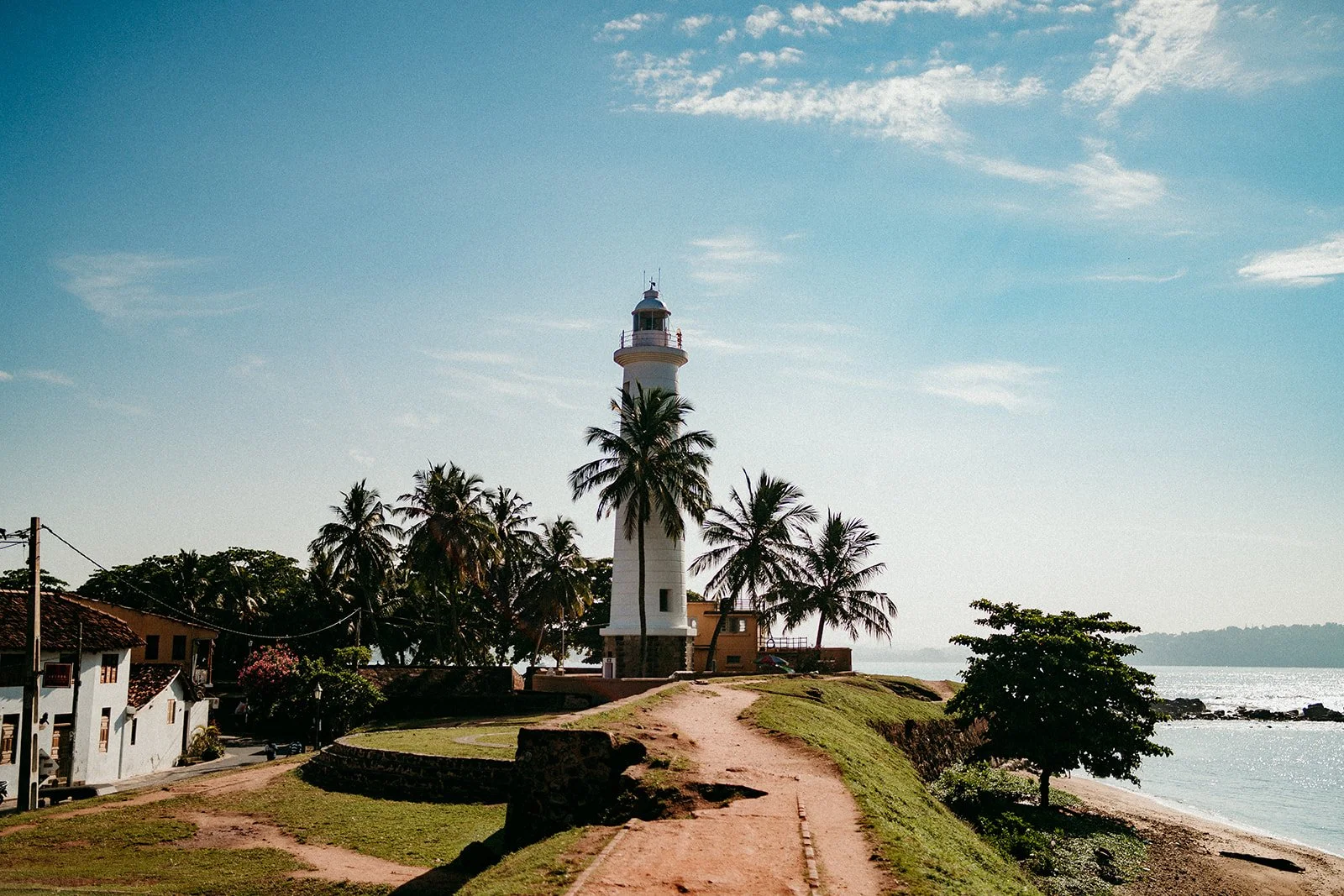 The historic lighthouse at Galle Fort in Sri Lanka, framed by palm trees and coastal views