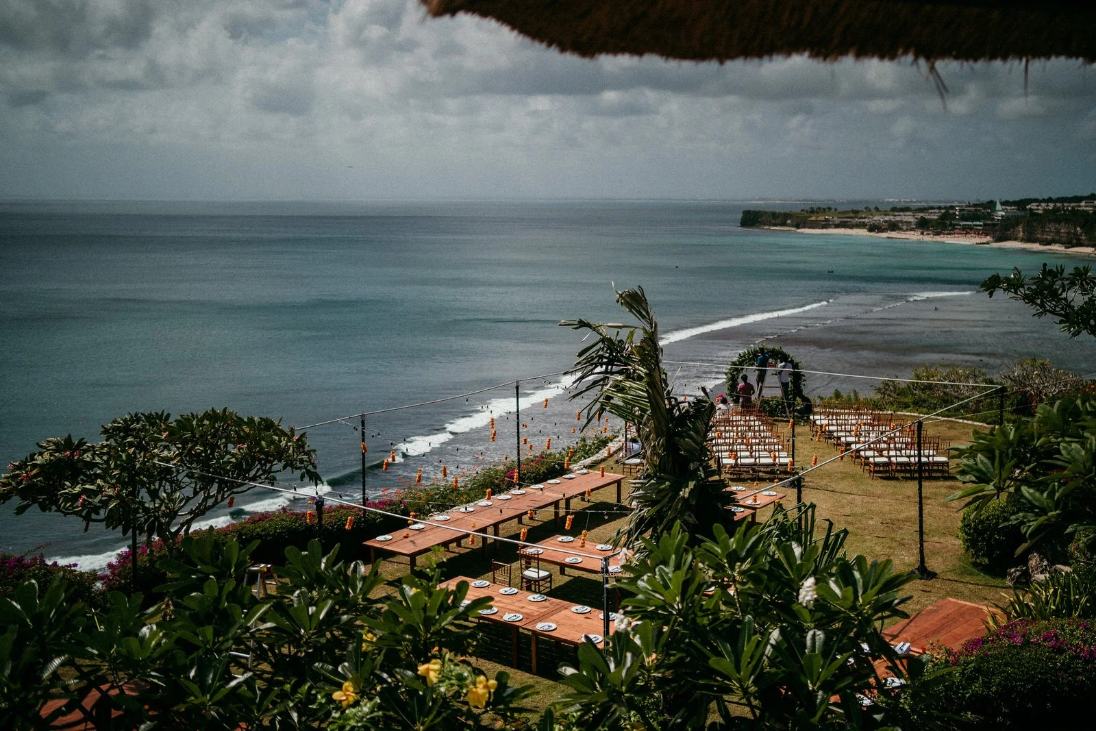 Clifftop wedding reception setup overlooking the ocean in Bali, with long dining tables and ceremony chairs facing the sea