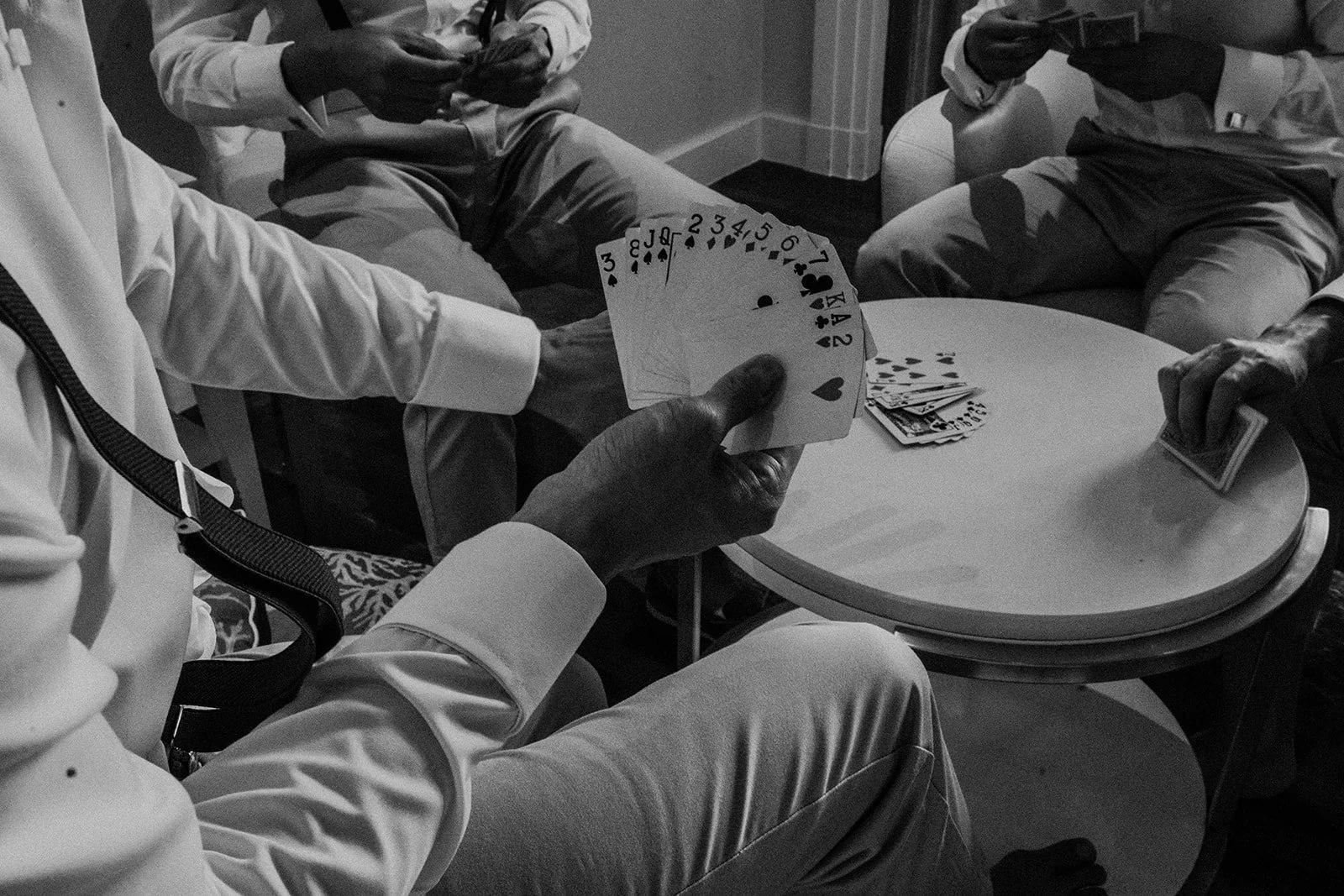 Groomsmen playing poker before wedding ceremony — candid documentary photography by Weddings by Qay