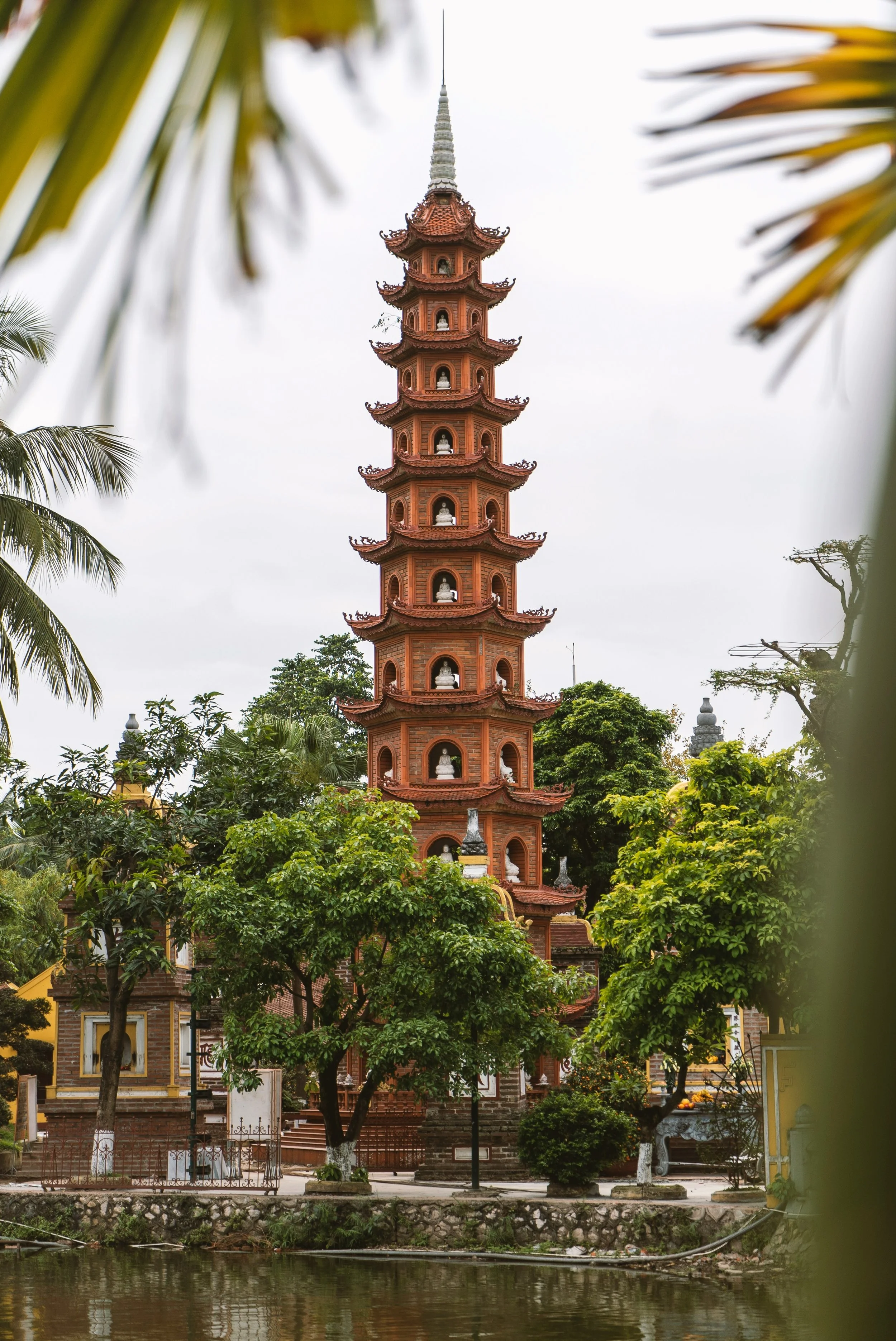 Tran Quoc Pagoda, an eleven-story terracotta tower on Hanoi's West Lake, framed by palm leaves