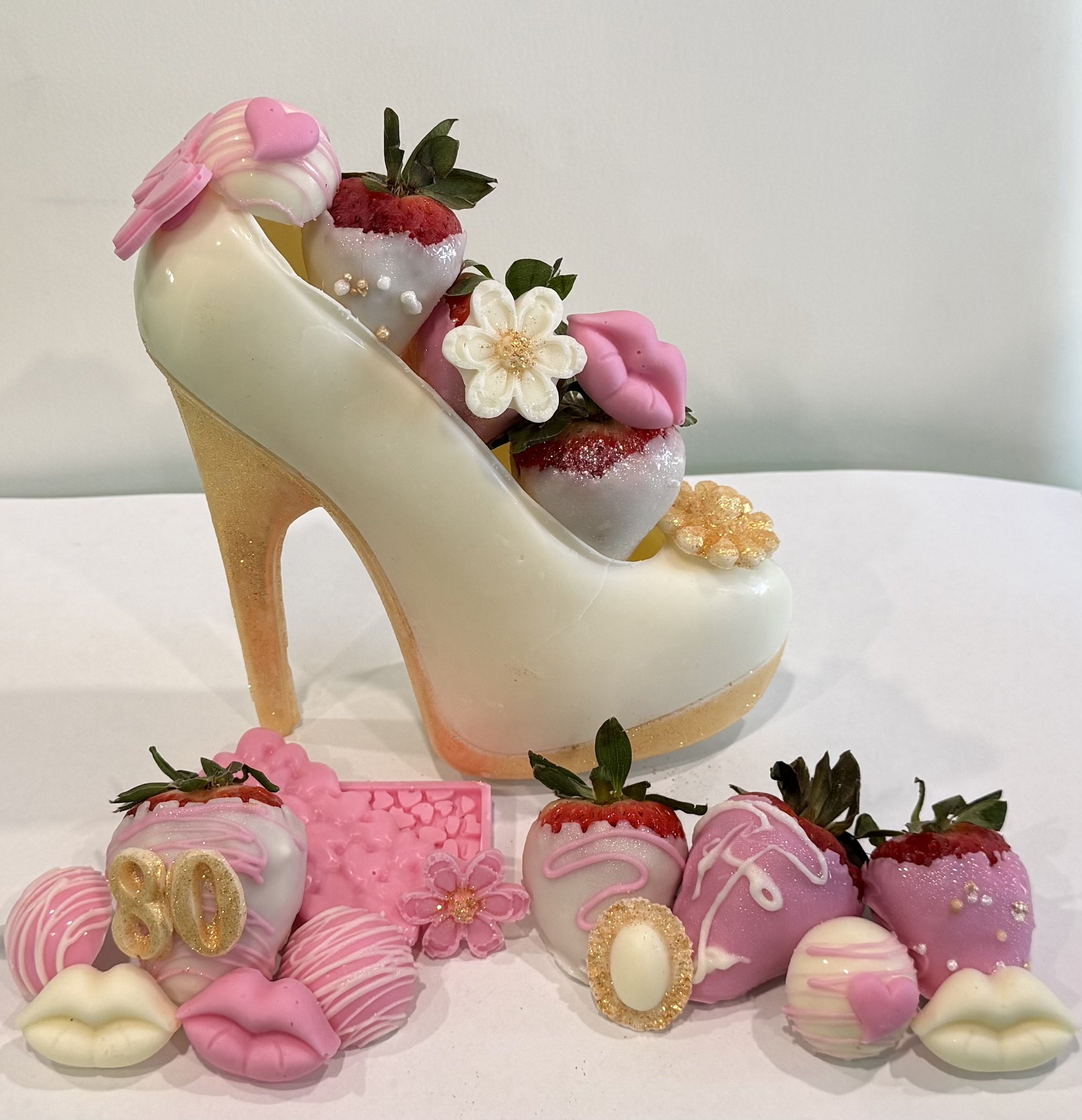 Pink and white decorated cookies with strawberries and flowers on a white surface.