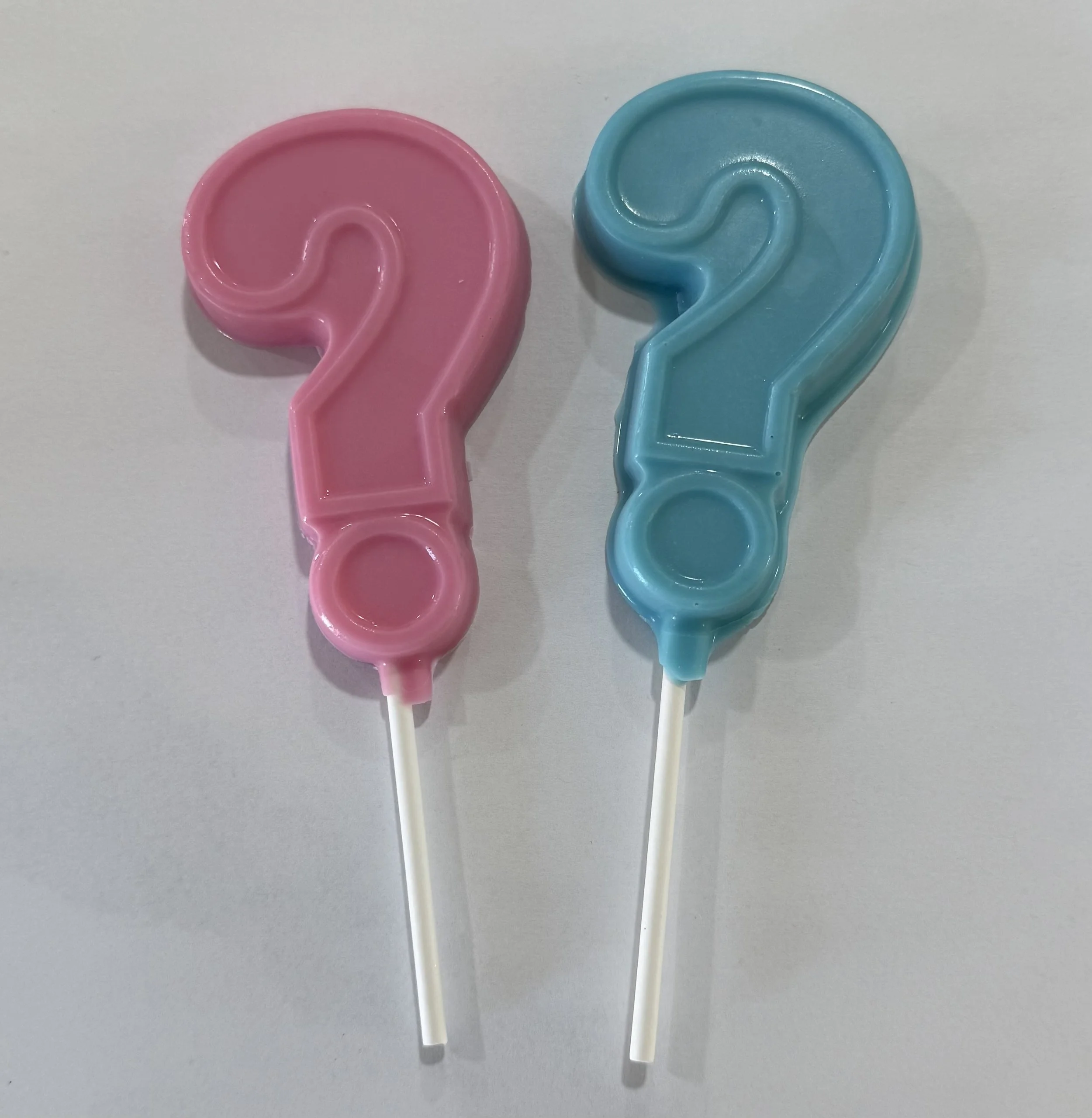Two birthday candles shaped like the number 2, one pink and one blue, placed side by side on a white surface.