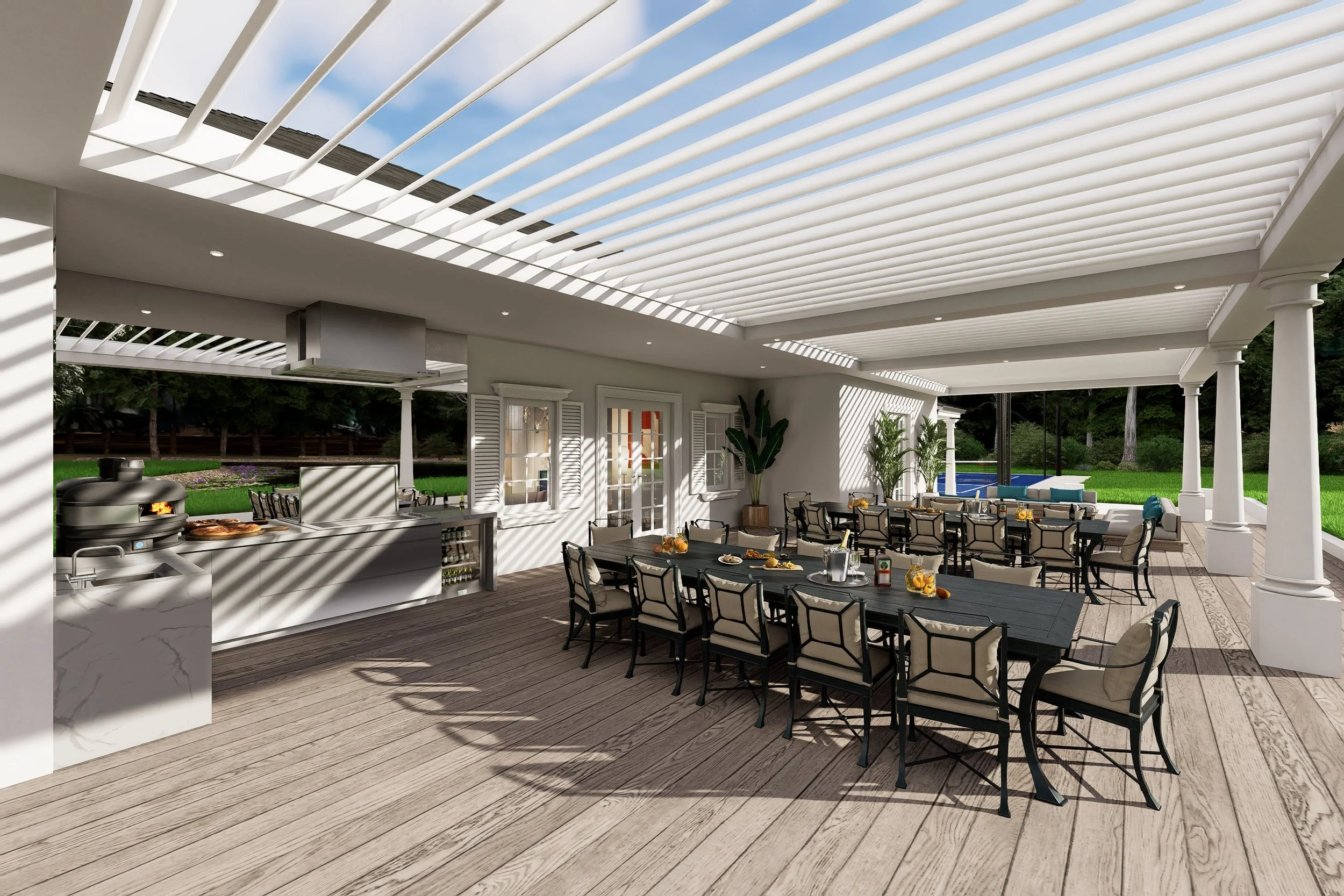Outdoor patio area with a large rectangular dining table and black chairs underneath a white pergola with slatted roof. There are plates of food, pitchers, and glasses on the table. The space is adjacent to a house with white walls, windows with shutters, and houseplants. In the background, lush greenery and trees can be seen, along with a glimpse of a swimming pool.