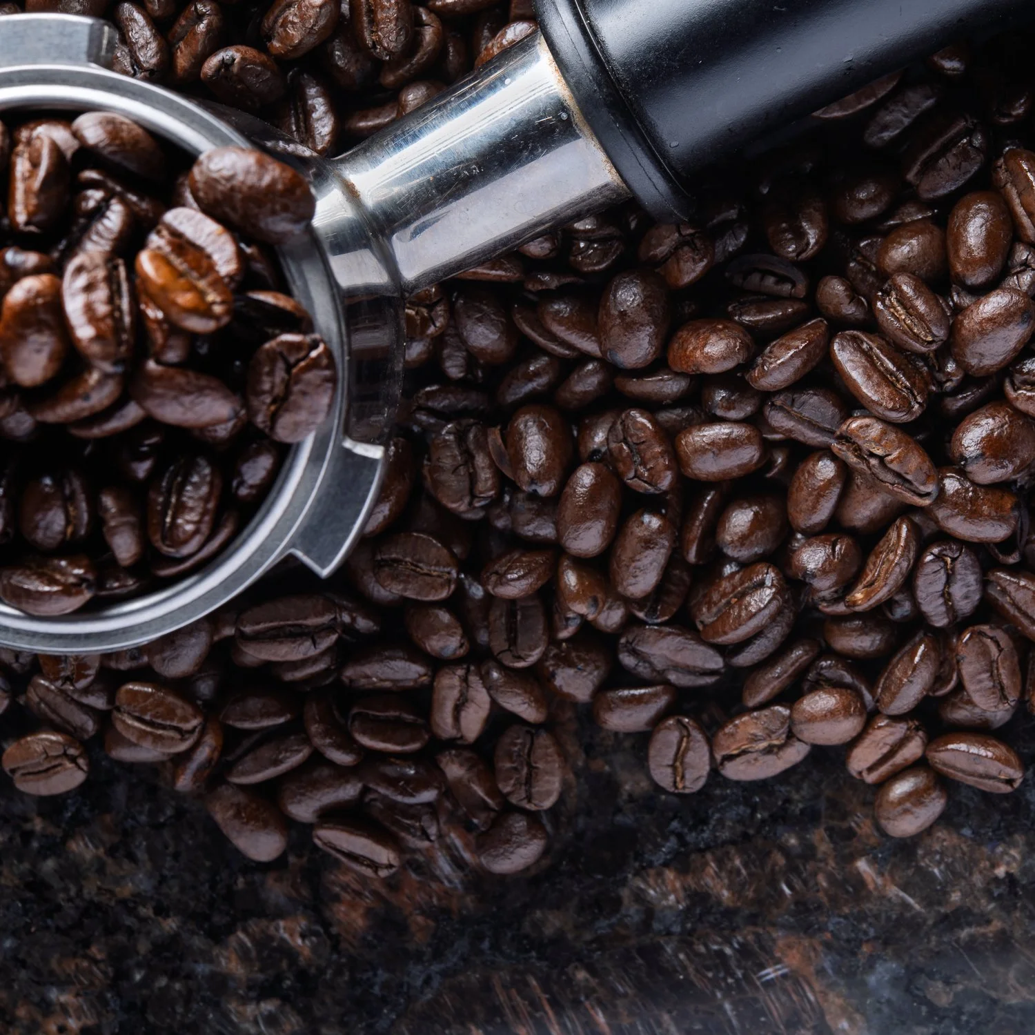 Coffee beans spilling from a portafilter.
