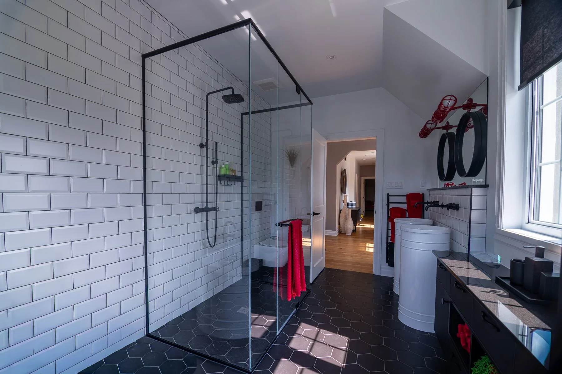 Bathroom with white subway tile, a black-framed glass shower enclosure, and black hexagon floor tile