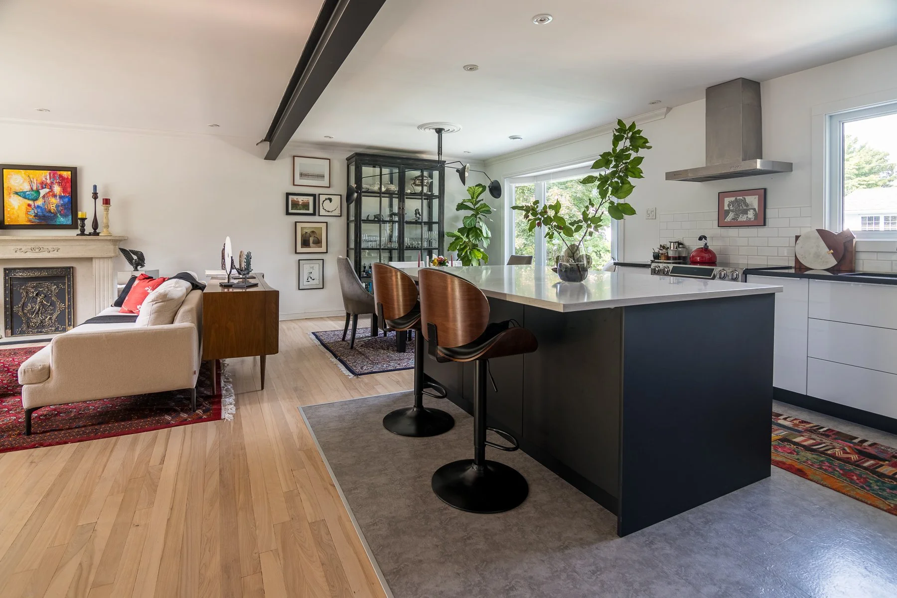 Open-plan living, dining, and kitchen resolved along one sightline, anchored by a dark island under a marble counter