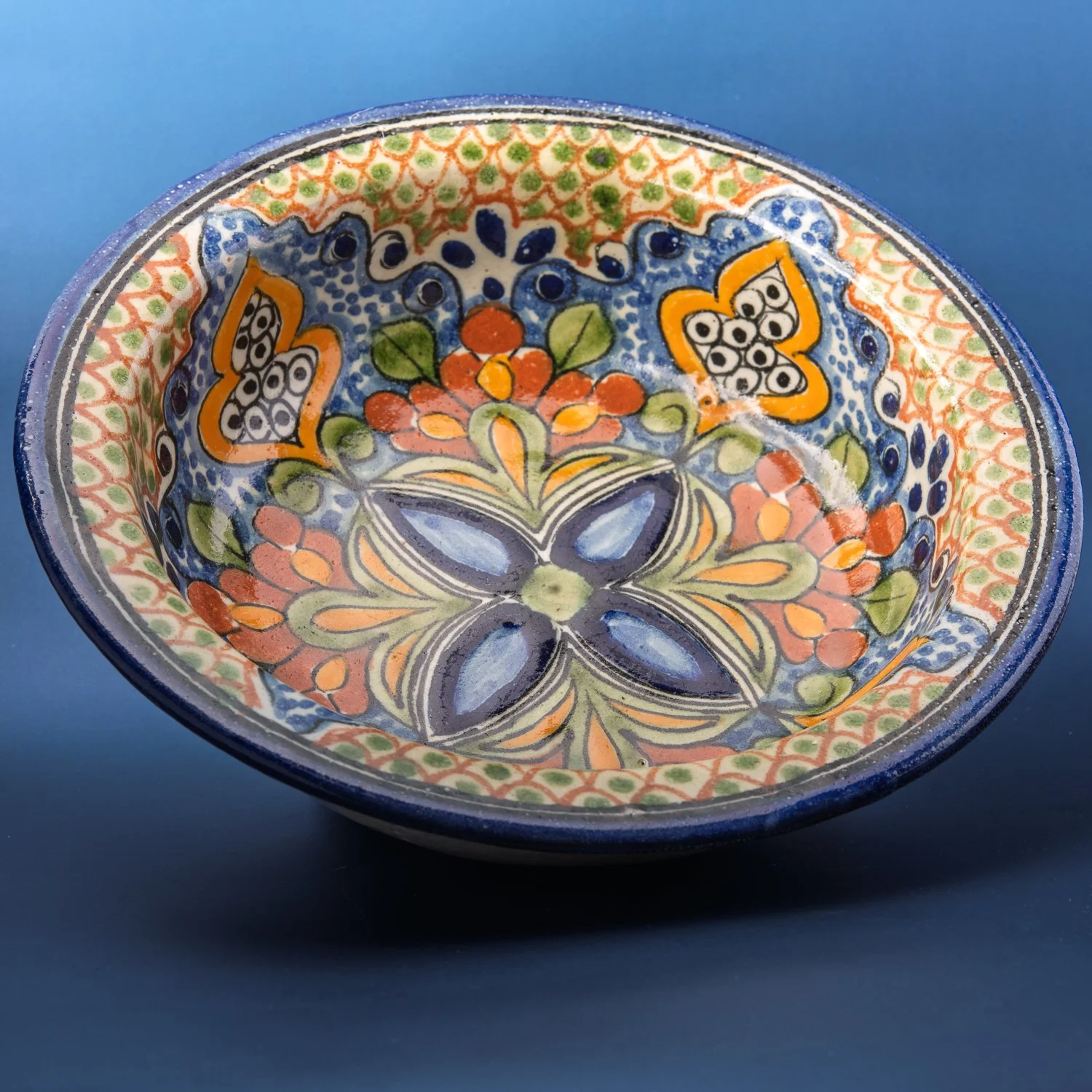 A hand-painted Talavera bowl with blue and orange floral decoration.