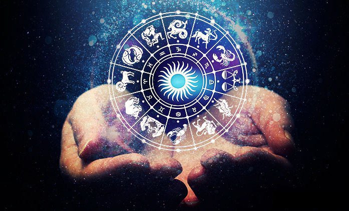 Person holding a zodiac wheel with constellation symbols glowing against a starry background.