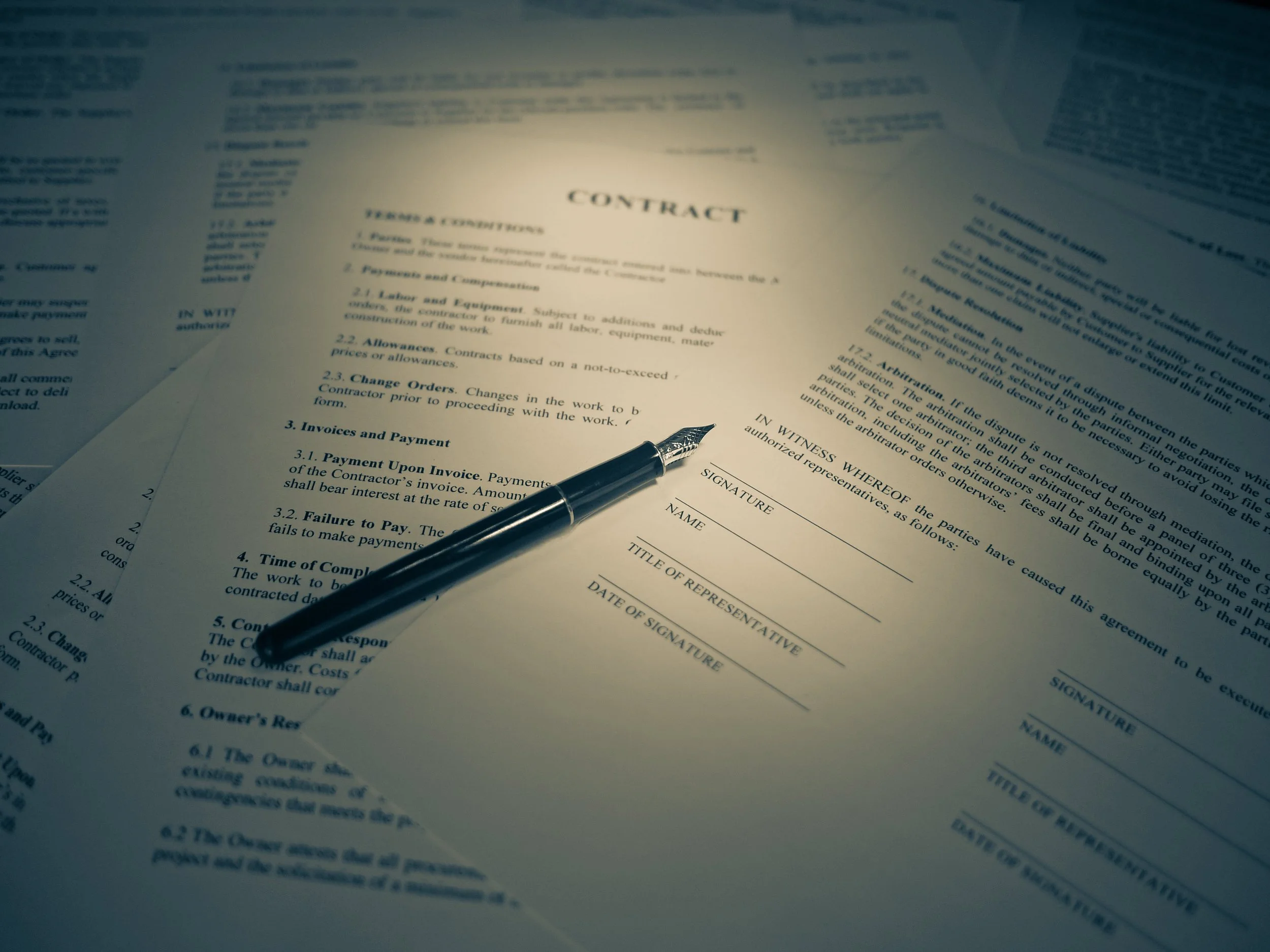 Close-up of a legal contract document with a black pen resting on top of it.