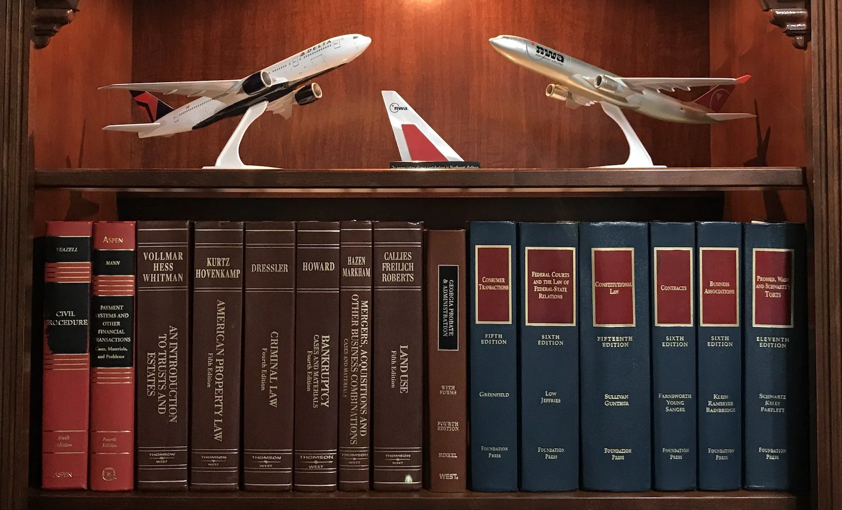 Model airplanes displayed on top of a bookshelf filled with law books.